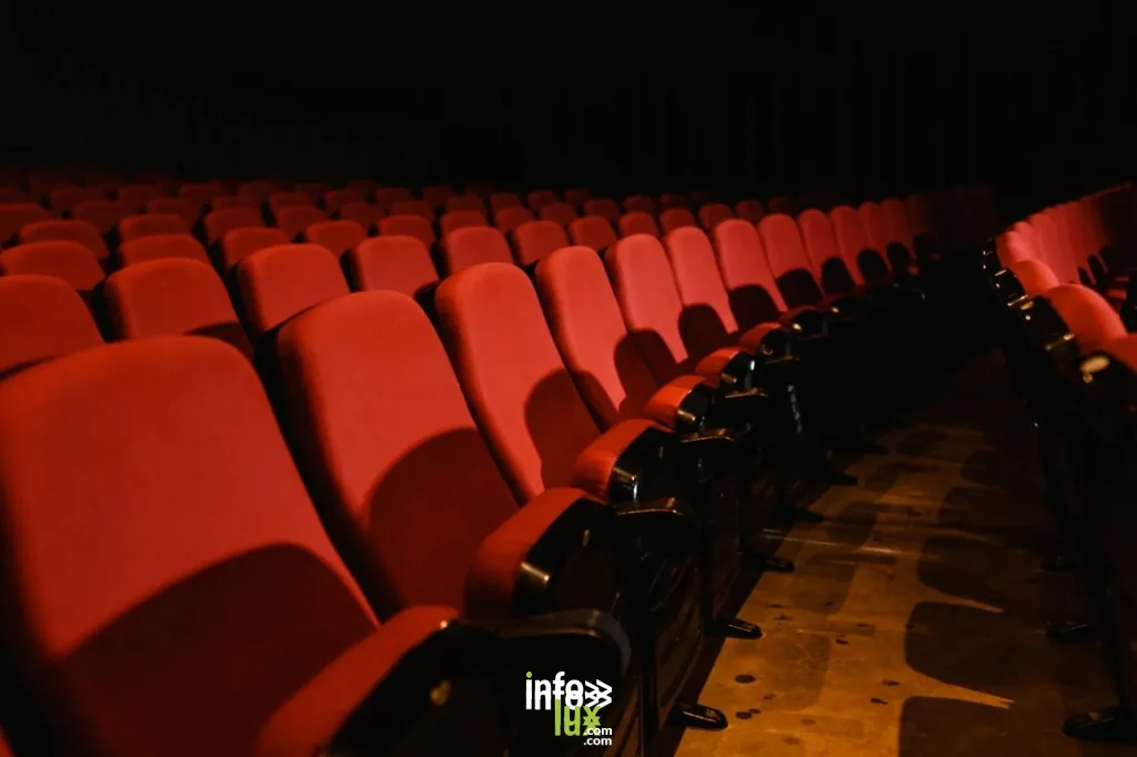 Des rangées de sièges rouges vides dans un cinéma faiblement éclairé, parfait pour des thèmes de cinéma.