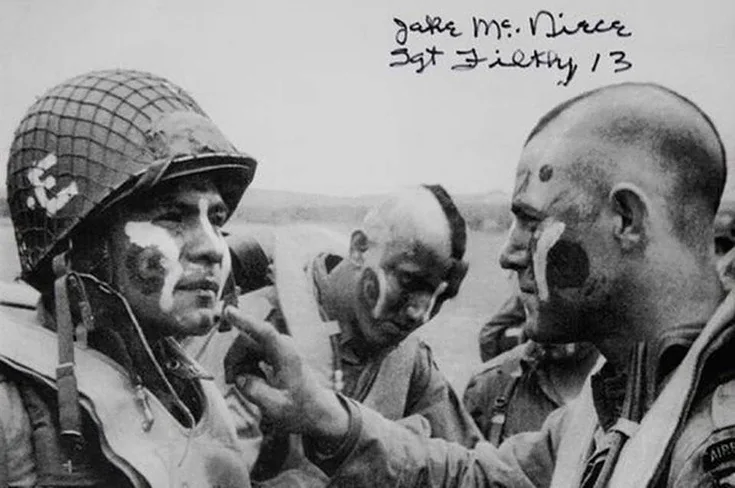 Le sergent Jake McNiece, coupe a l'iroquoise, applique des traits de peinture sur le visage d'un parachutiste des Filthy Thirteen le 5 juin 1944
