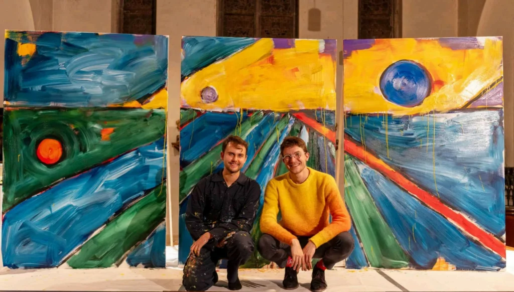 Jérémie Queyras (à gauche) et le violoncelliste Pierre Fontenelle, accroupis devant une toile monumentale en trois panneaux réalisée en performance