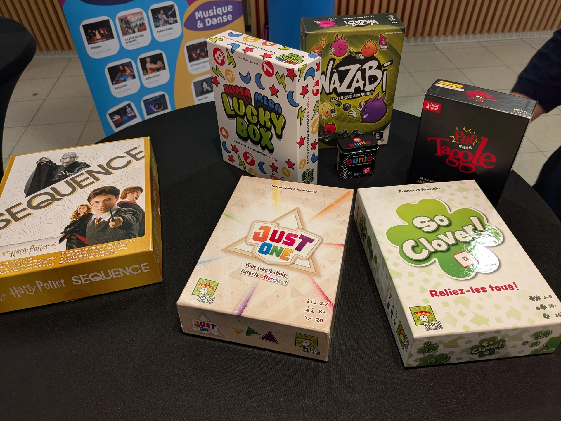 Boîtes de jeux de société Just One, So Clover, Sequence Harry Potter, Nazabi et Taggle sur une table du Centre culturel de Bertrix