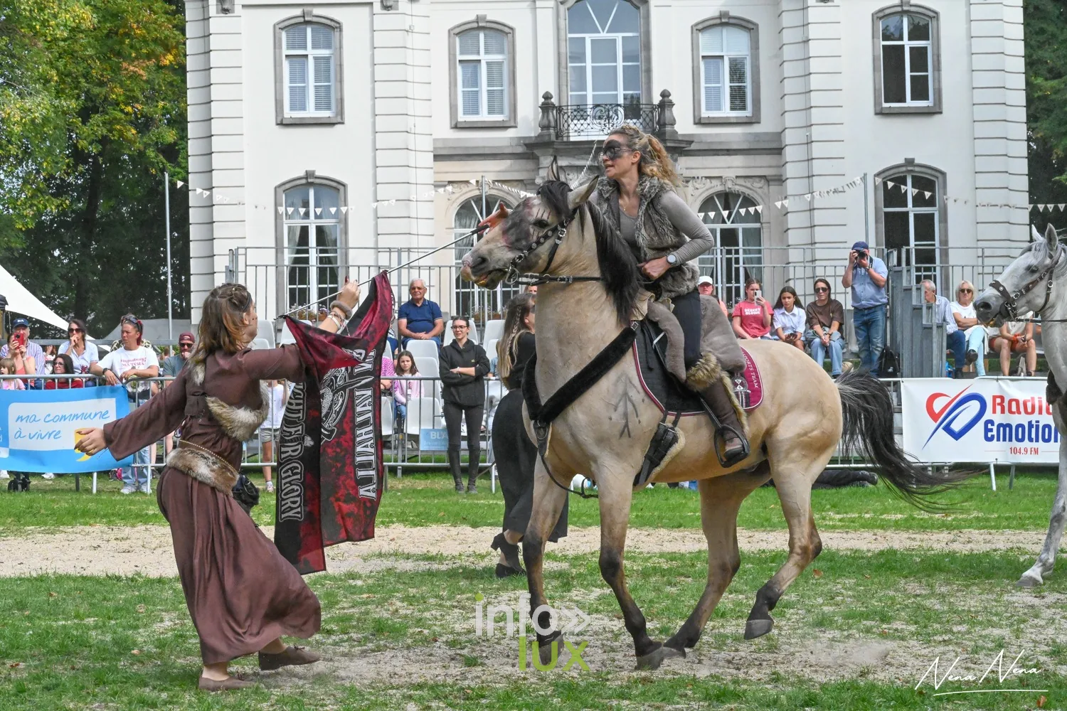 Journées du Cheval 2026 à Braine-l’Alleud, parc du Cheneau : une porte-bannière à pied accompagne une cavalière devant les tribunes