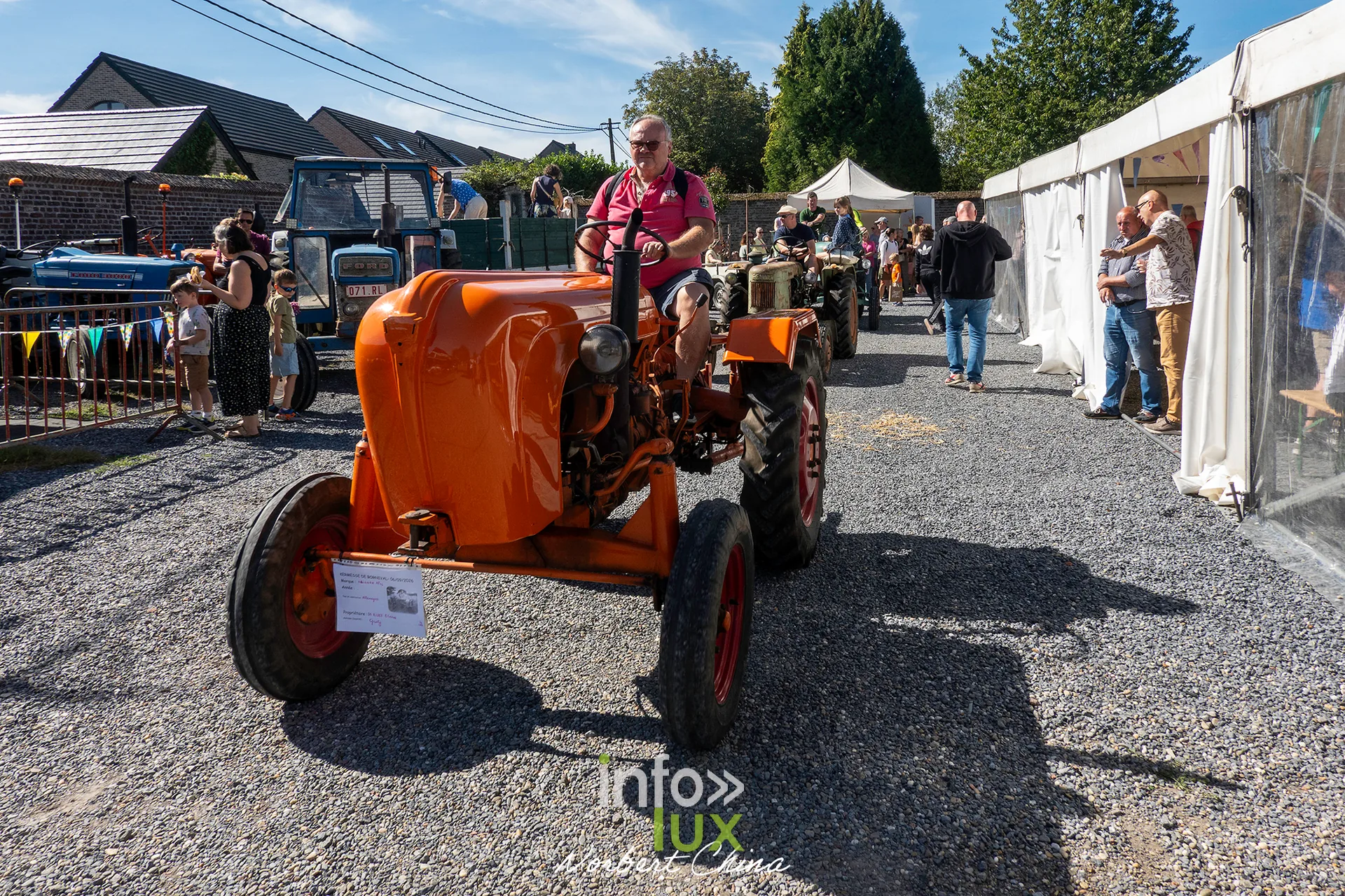 Un tracteur orange conduit par un participant entre les stands