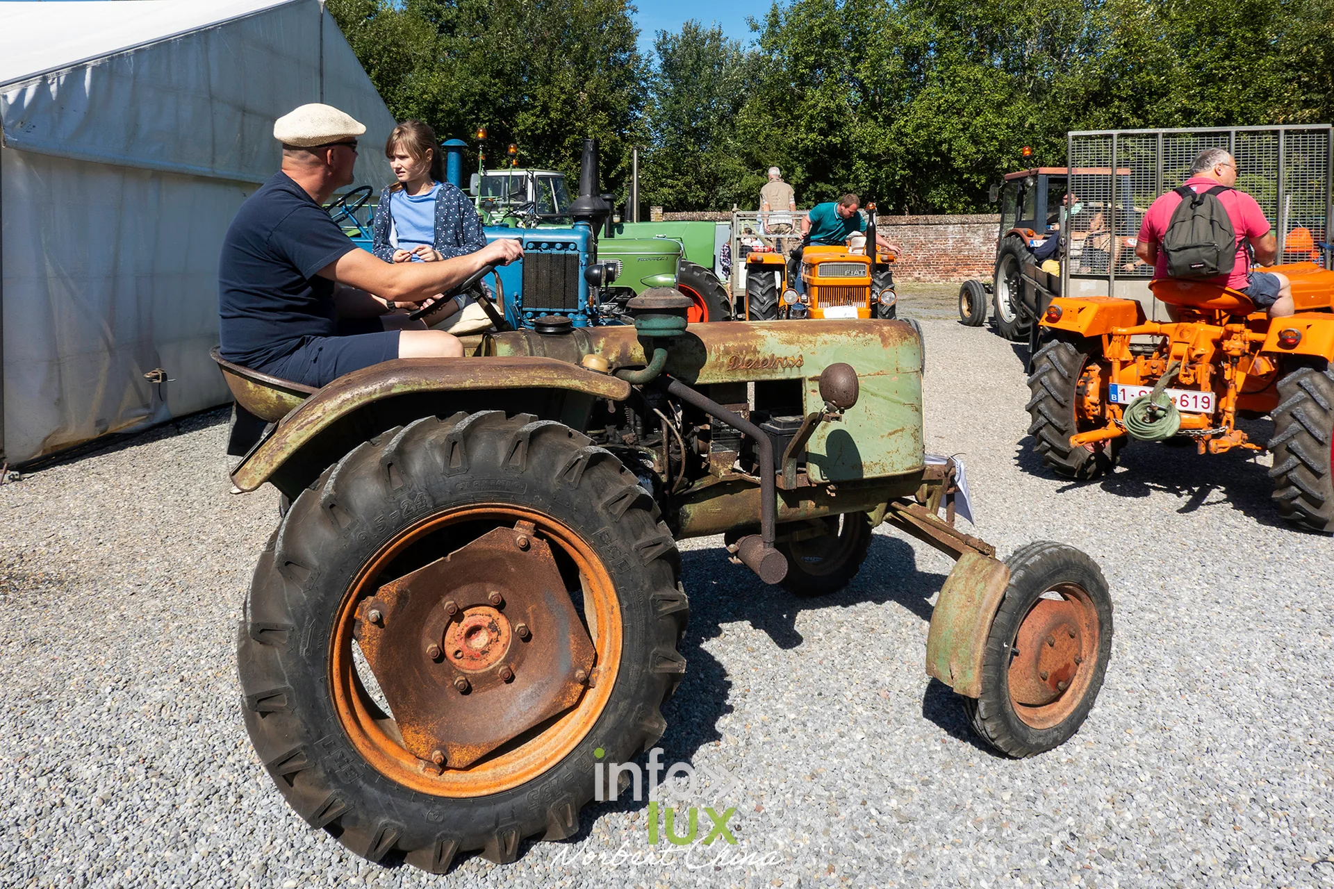Un homme en casquette conduit un tracteur vert sur le site