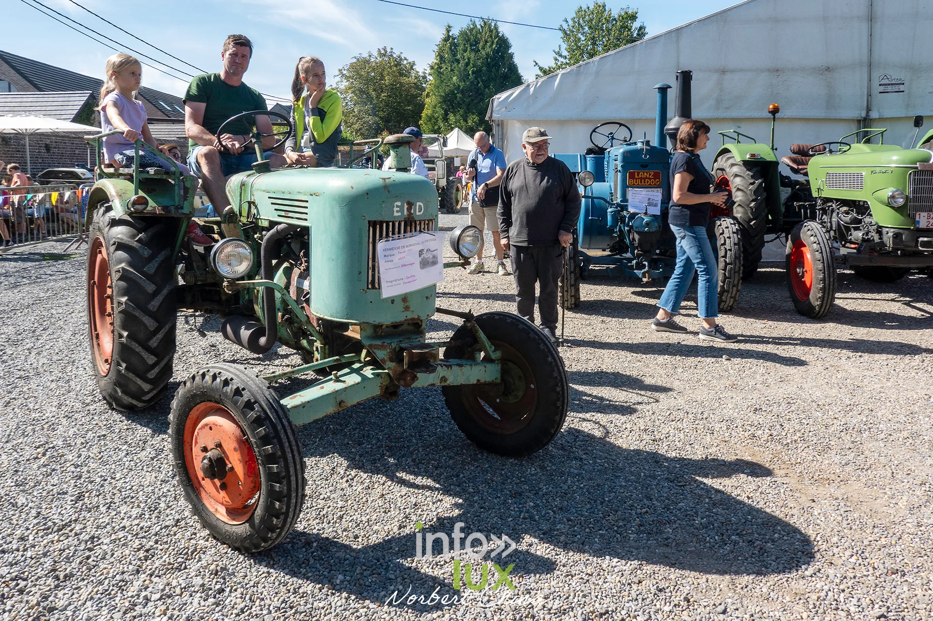 Un tracteur vert entouré de visiteurs pendant la kermesse