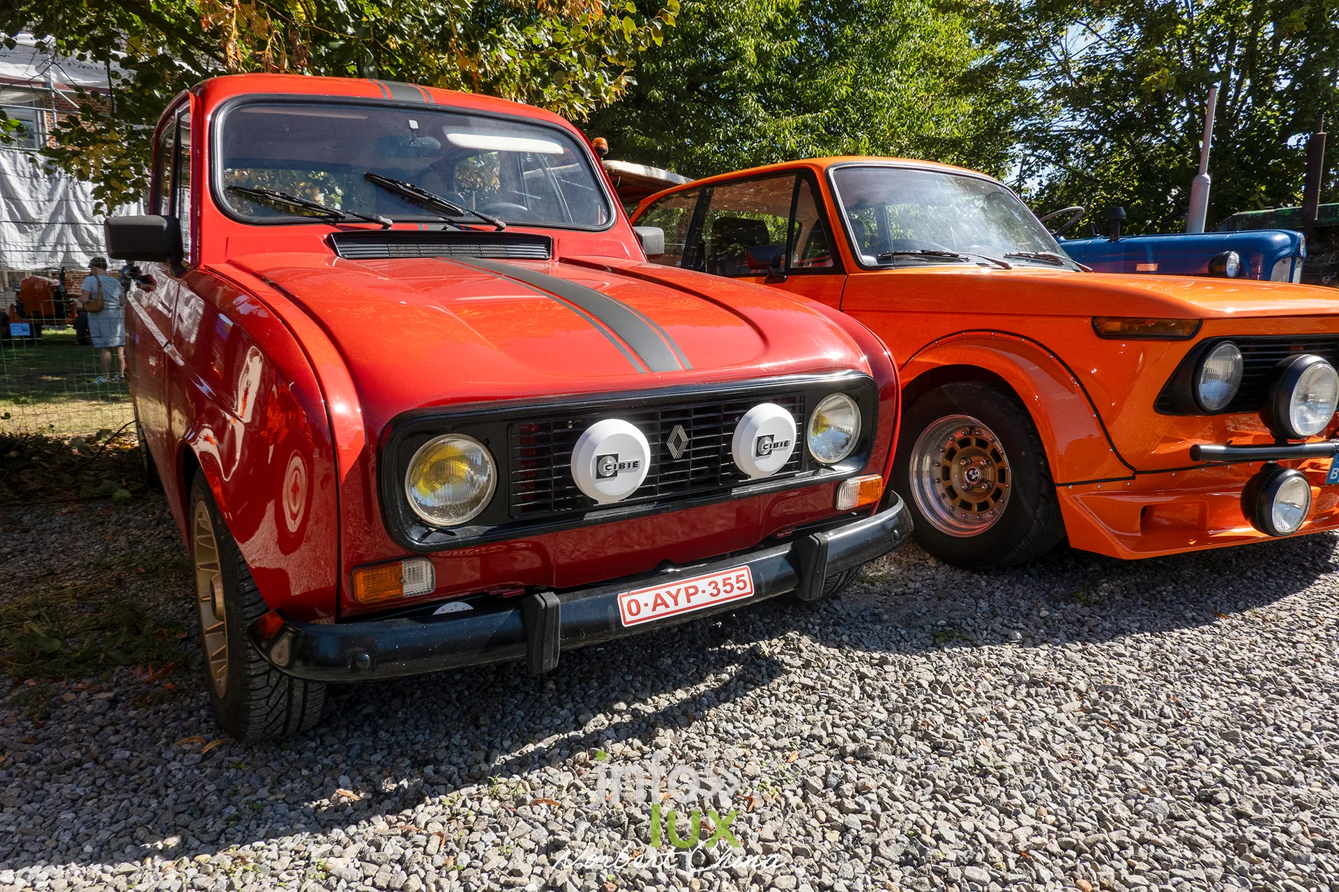 Voitures anciennes orange exposées à côté des tracteurs