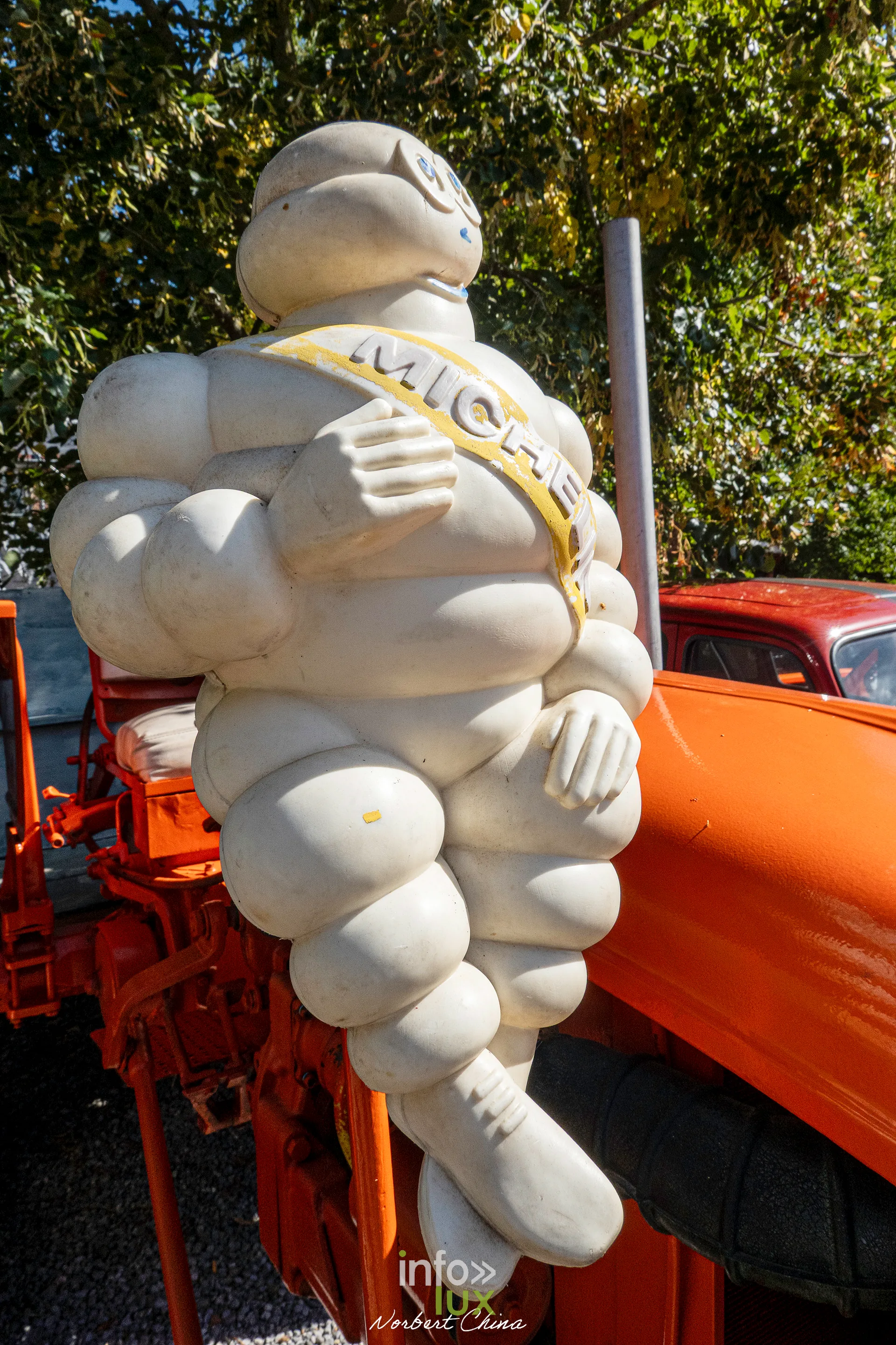 Un Bibendum Michelin posé sur un tracteur orange