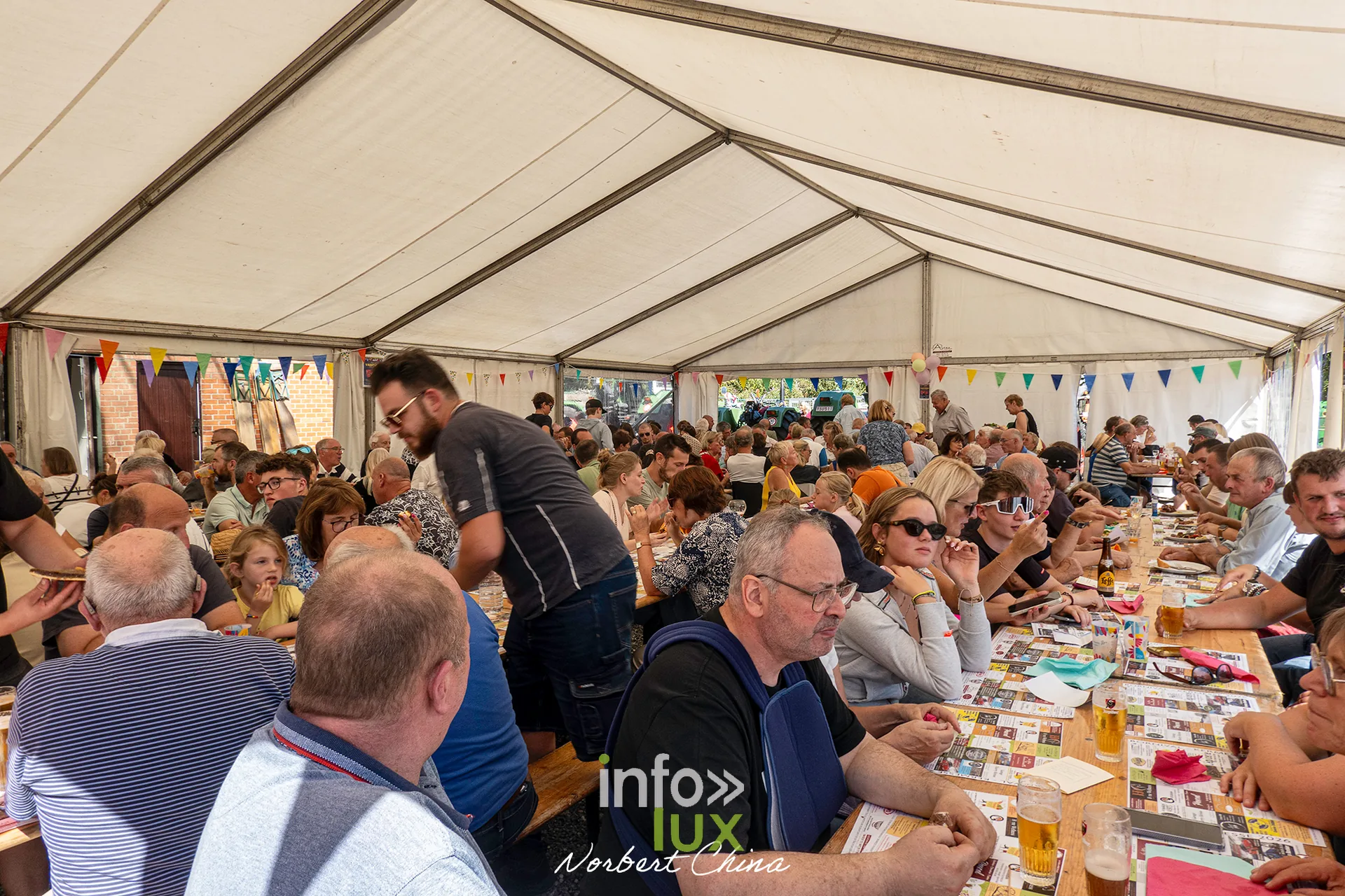 Vue large des tablées sous le chapiteau pendant le repas
