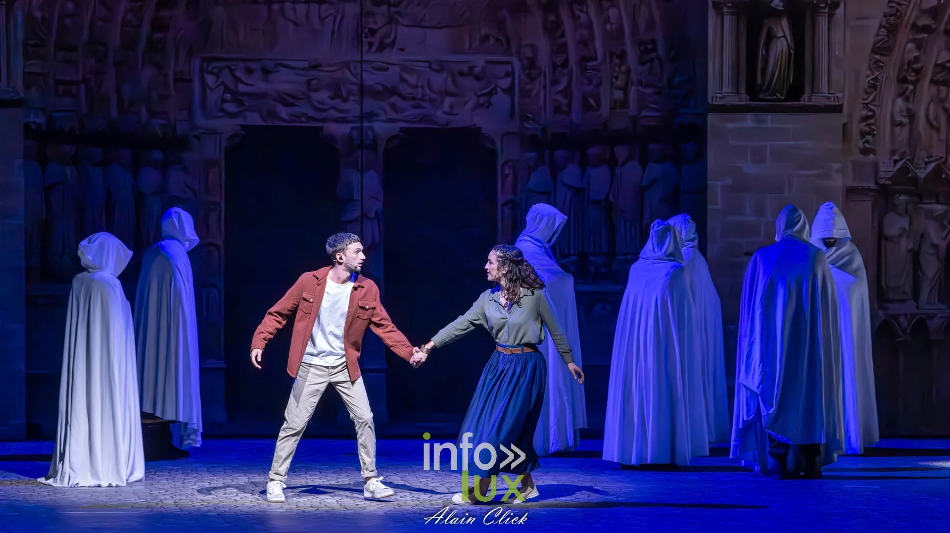 Un homme en veste rouge entouré de silhouettes en capes blanches, La Dame de Pierre