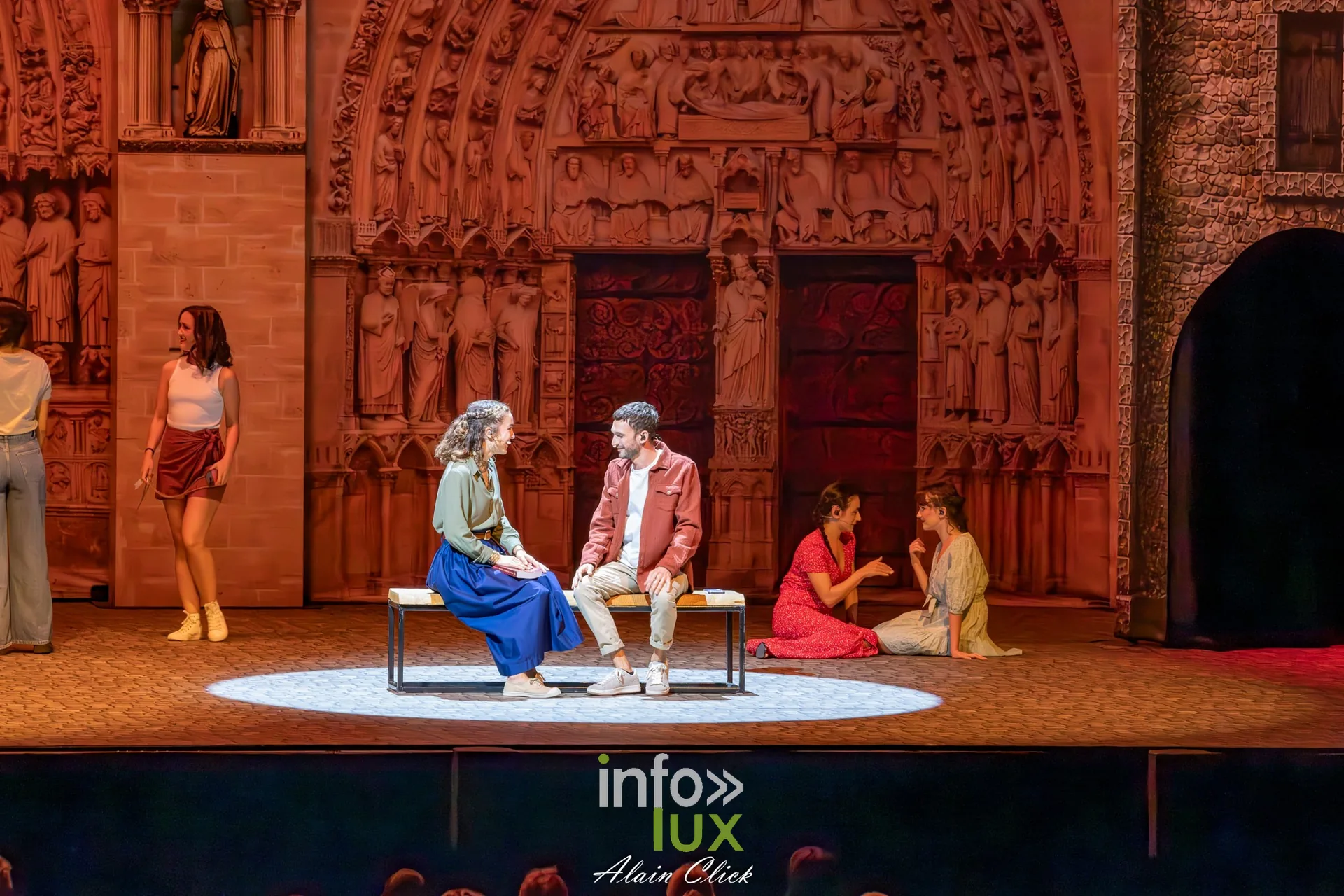 Prologue de La Dame de Pierre au Zénith de Nancy : des personnages en tenues contemporaines assis sur un banc devant le portail de Notre-Dame