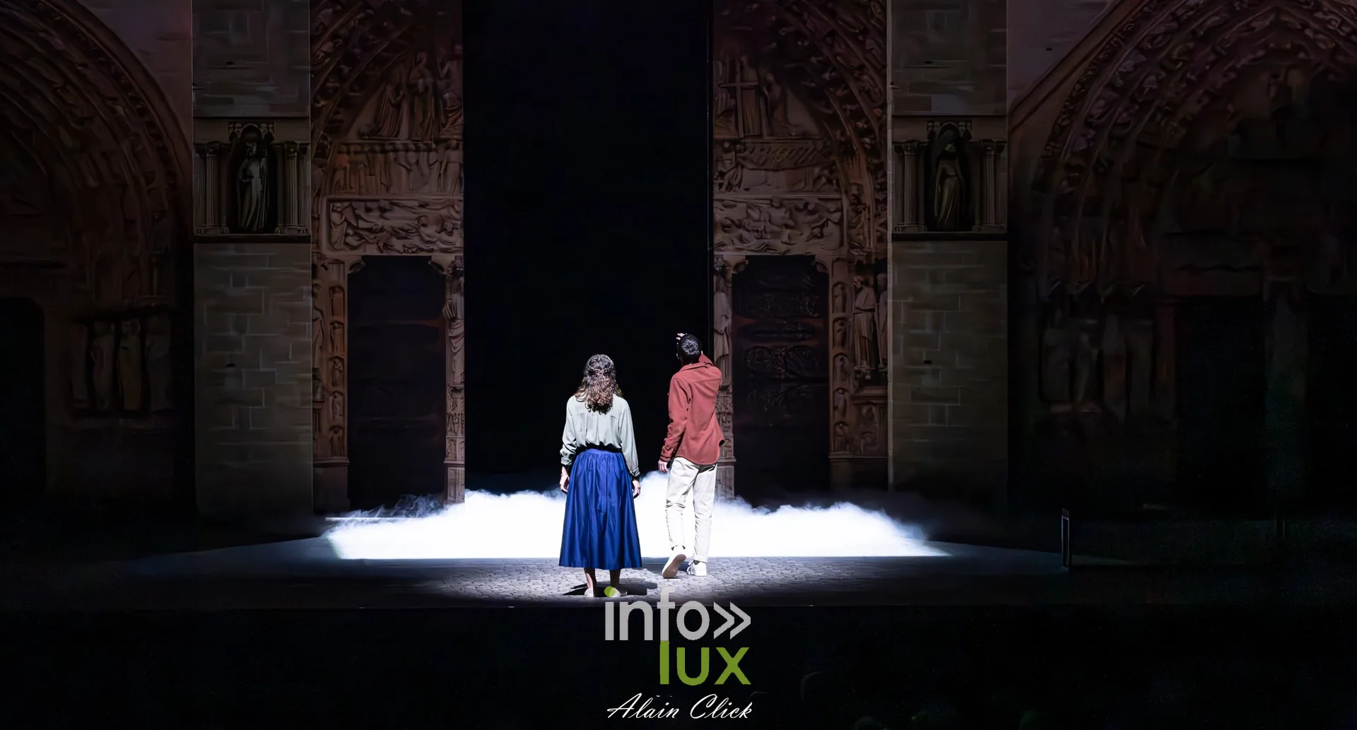 Deux personnages sous une lumière blanche au pied du portail, La Dame de Pierre