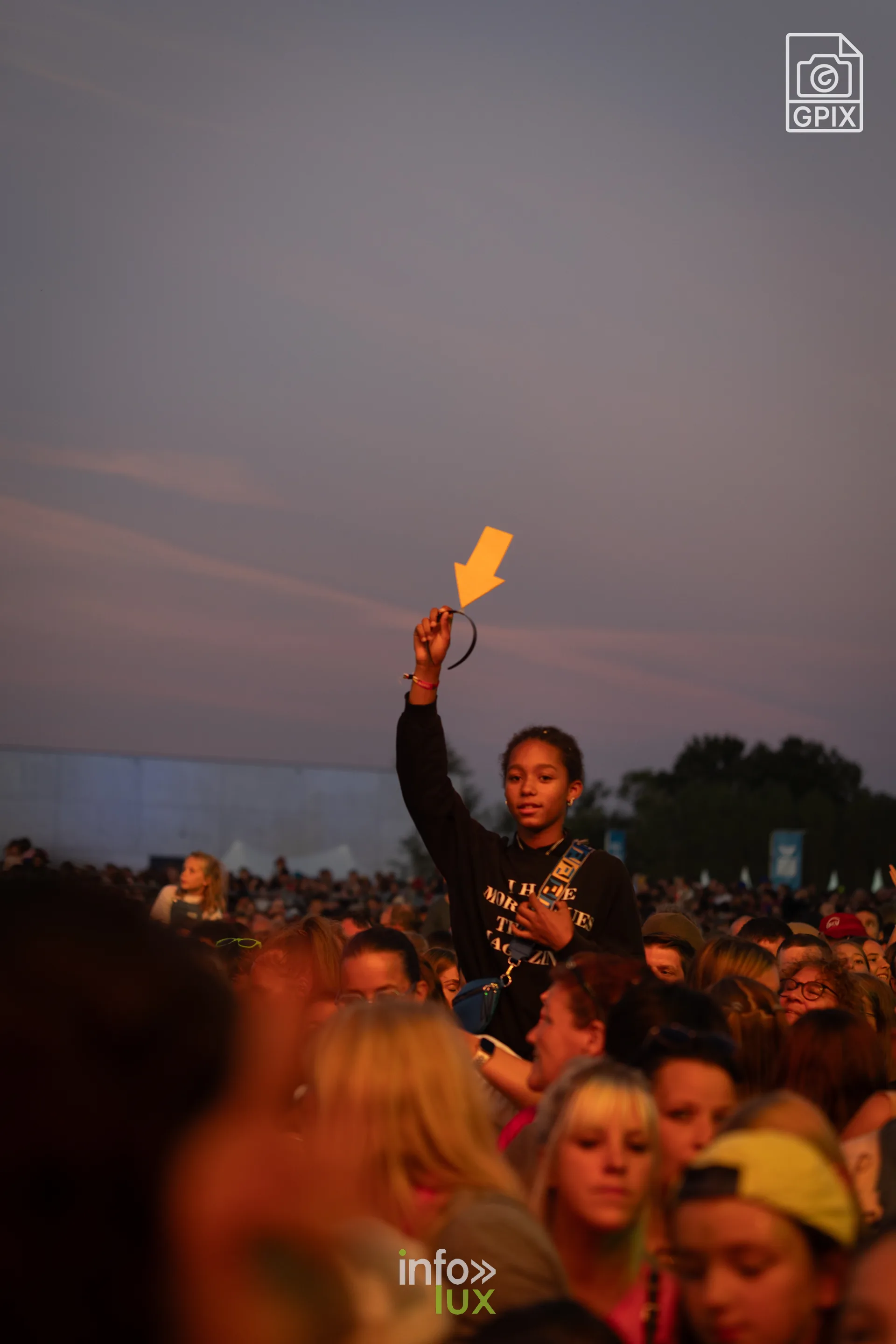 Un festivalier lève un fumigène dans la foule au crépuscule