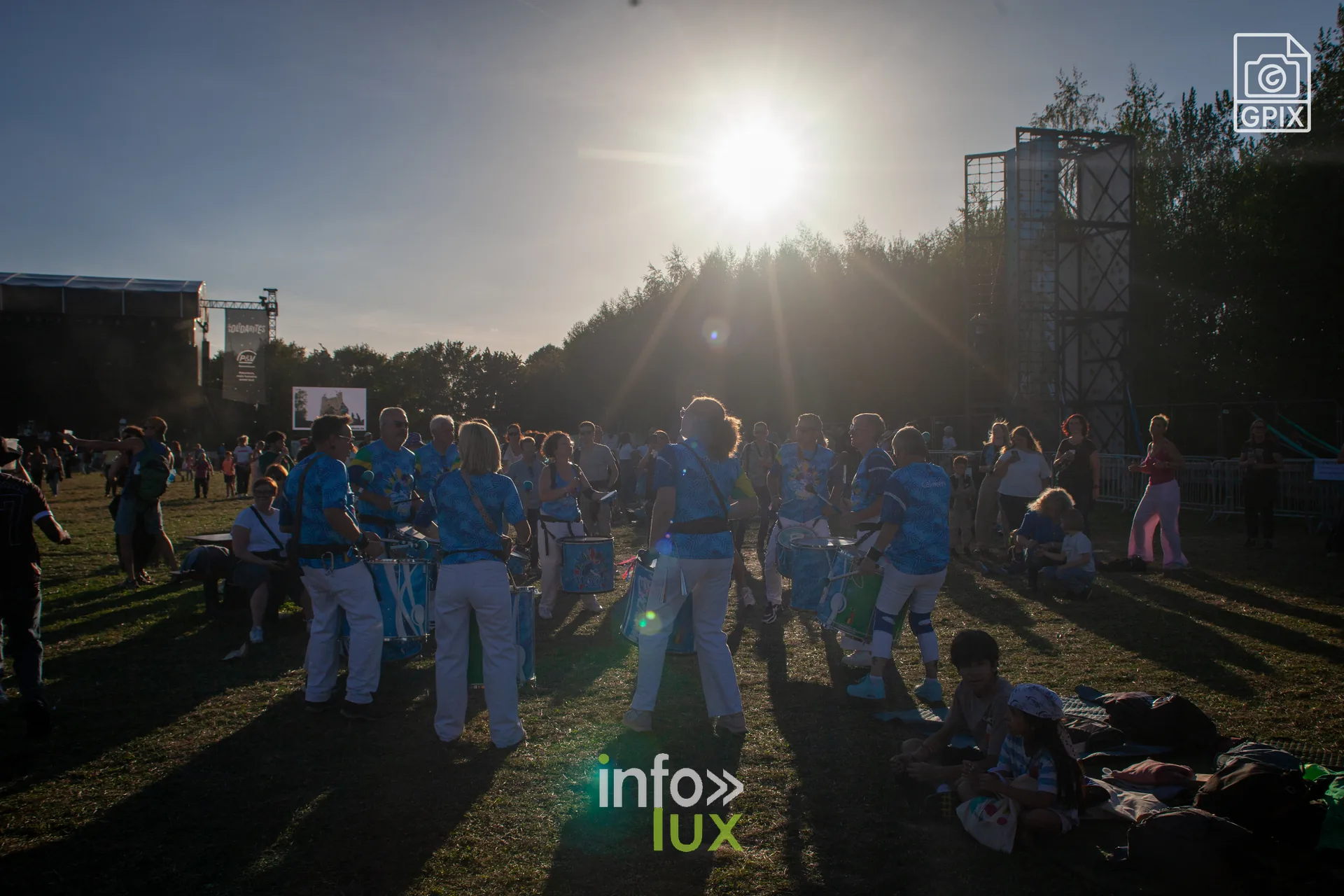 Une fanfare en tenue bleue traverse le site à contre-jour