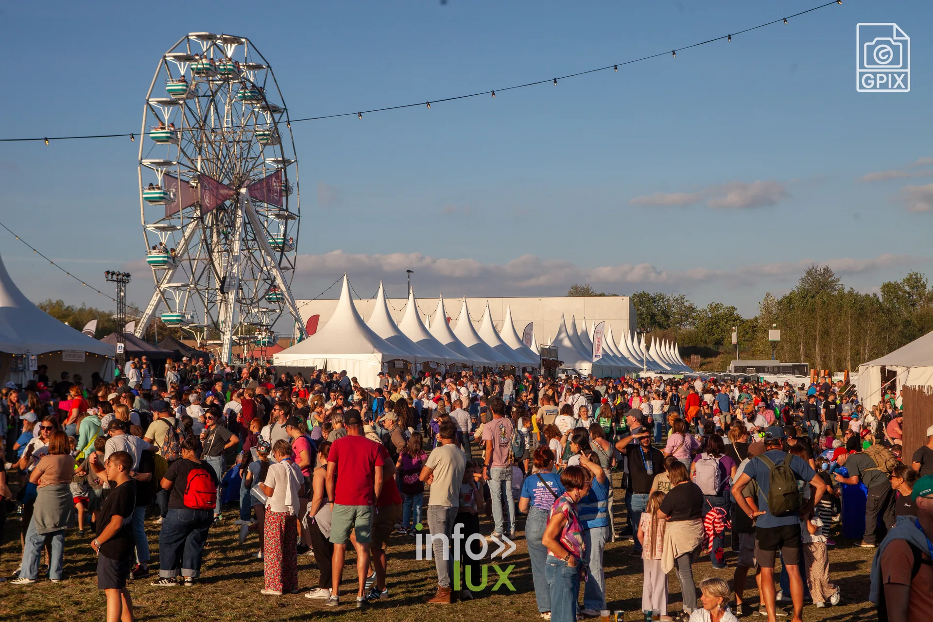 Vue large de la plaine du festival avec la grande roue et les chapiteaux