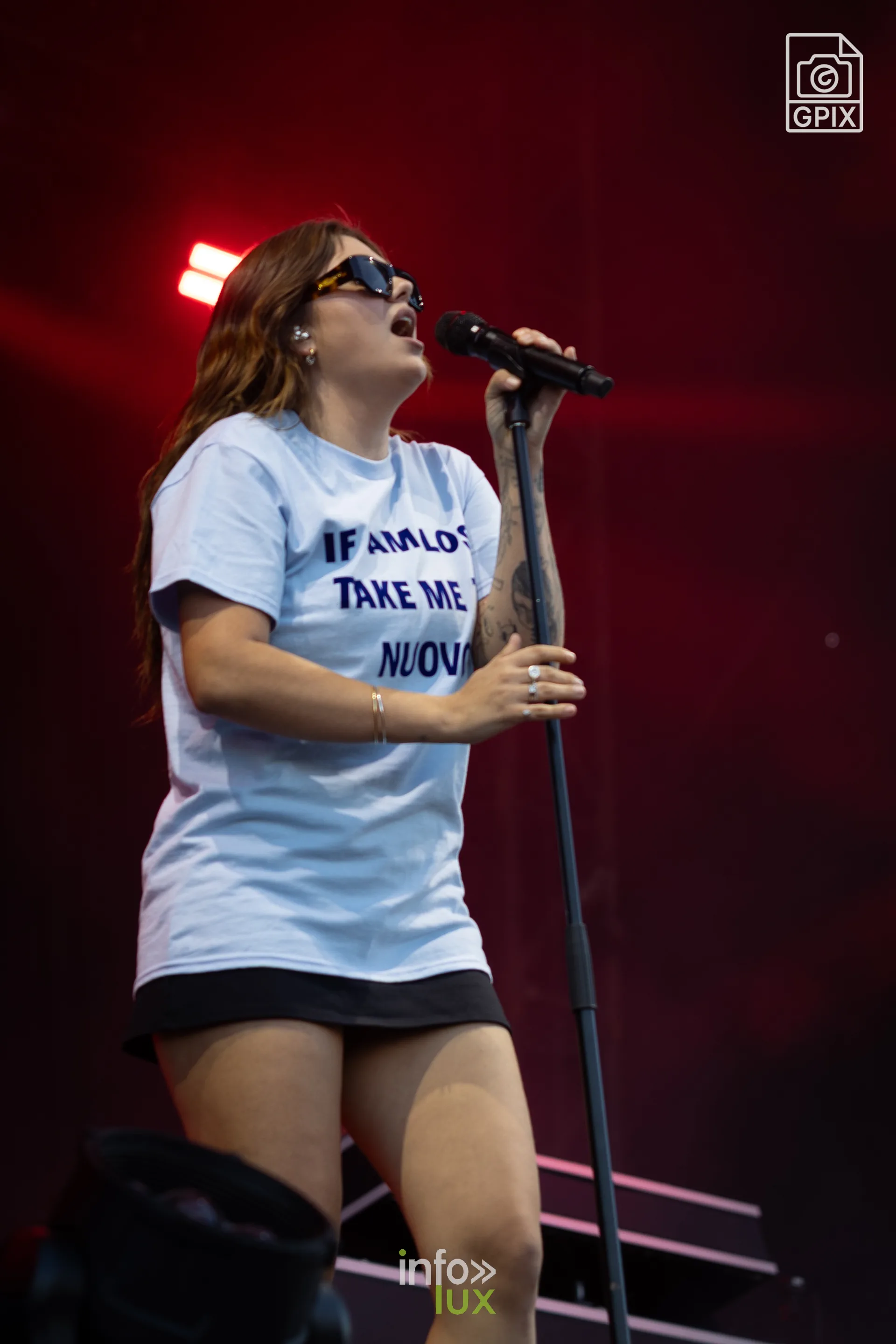 Louane chante en t-shirt clair sous les lumières rouges