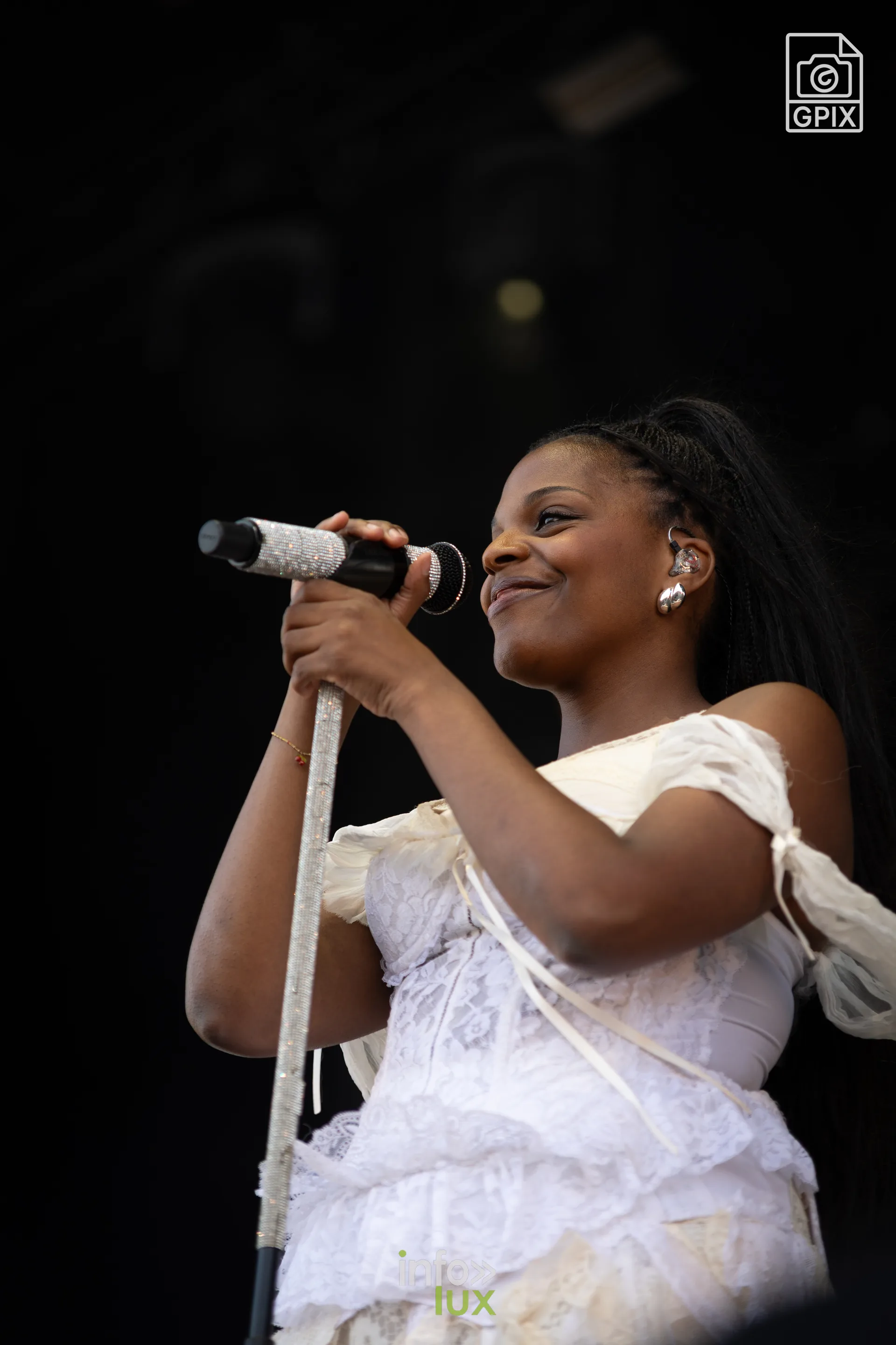Mentissa en robe blanche chante sur la Place des Arts