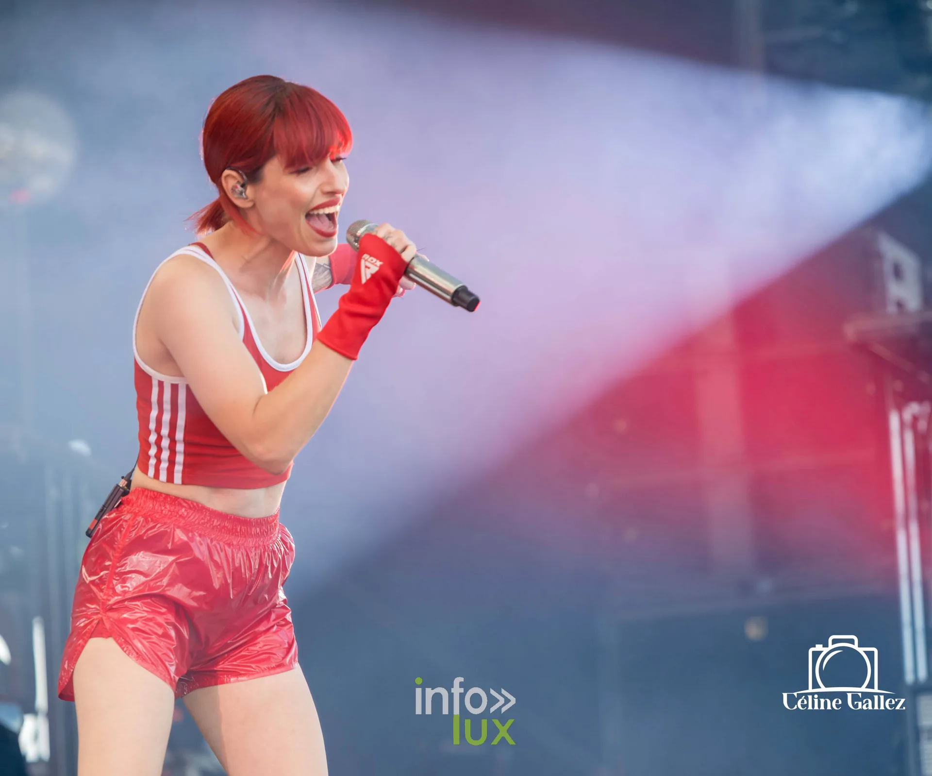Jennifer Ayache chante sous une lumière rouge, tenue rouge