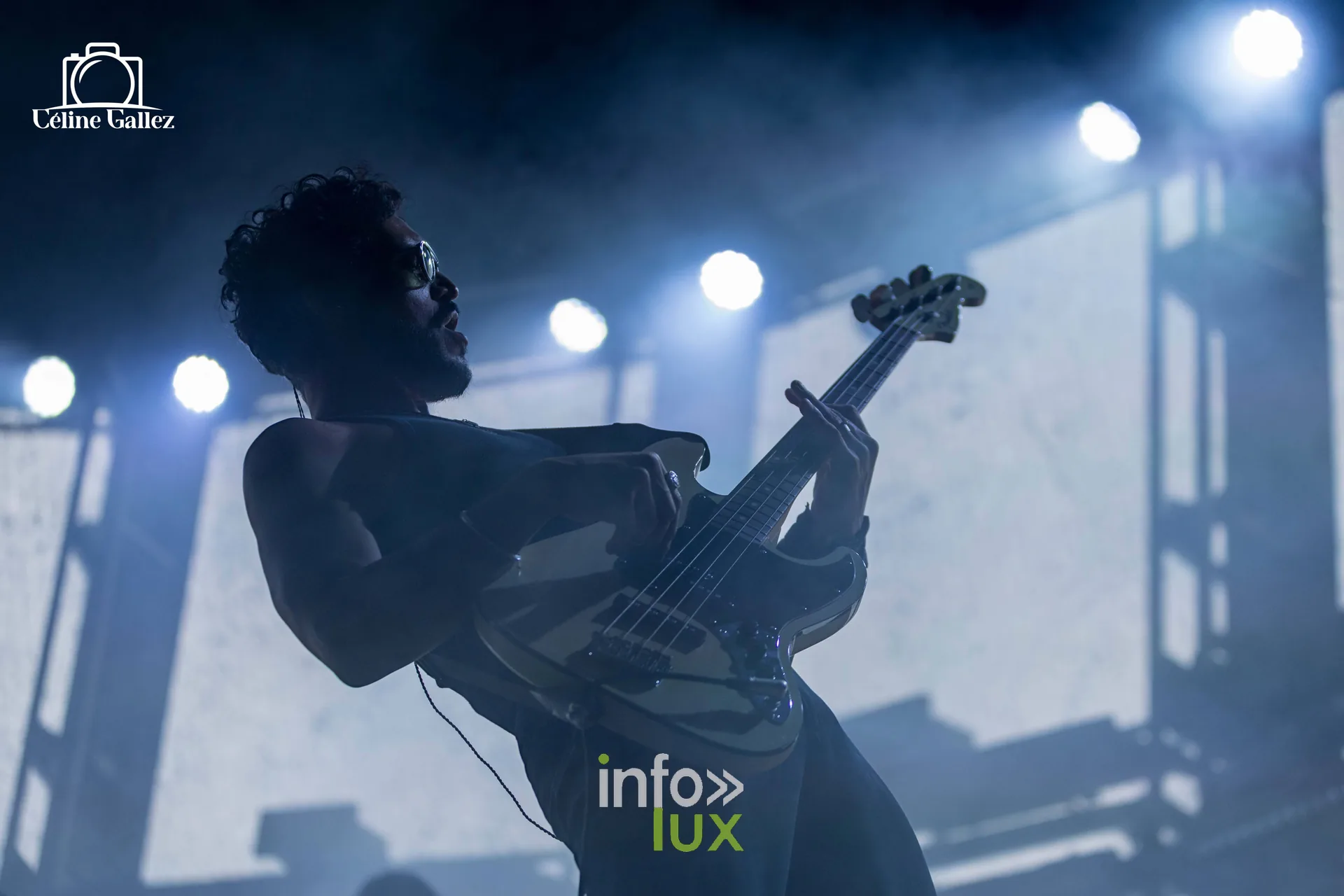 Un musicien en contre-jour avec sa basse devant un écran lumineux