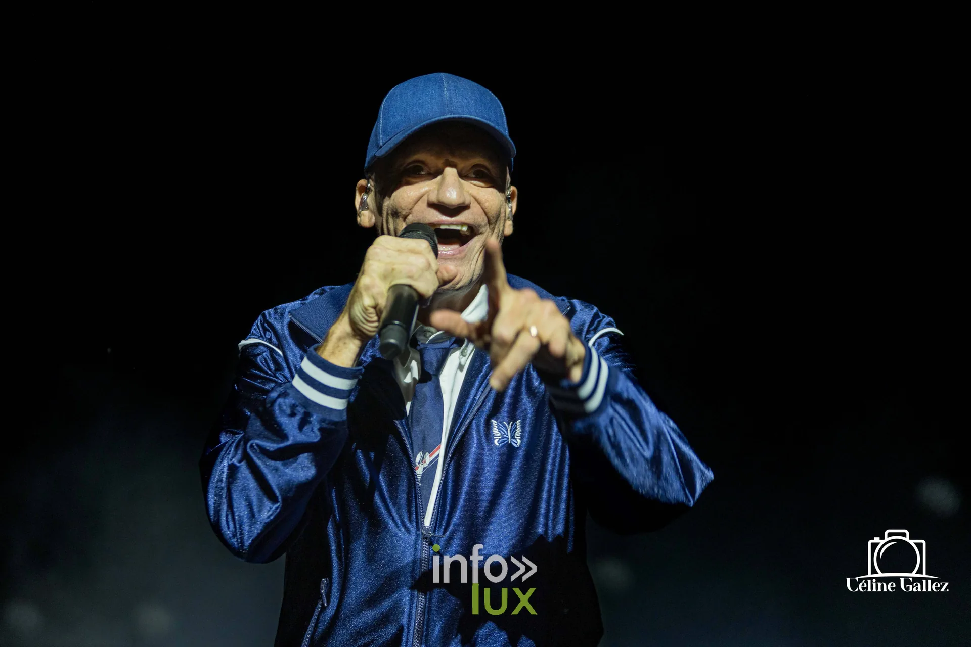 Gaëtan Roussel au micro, veste bleu nuit et casquette