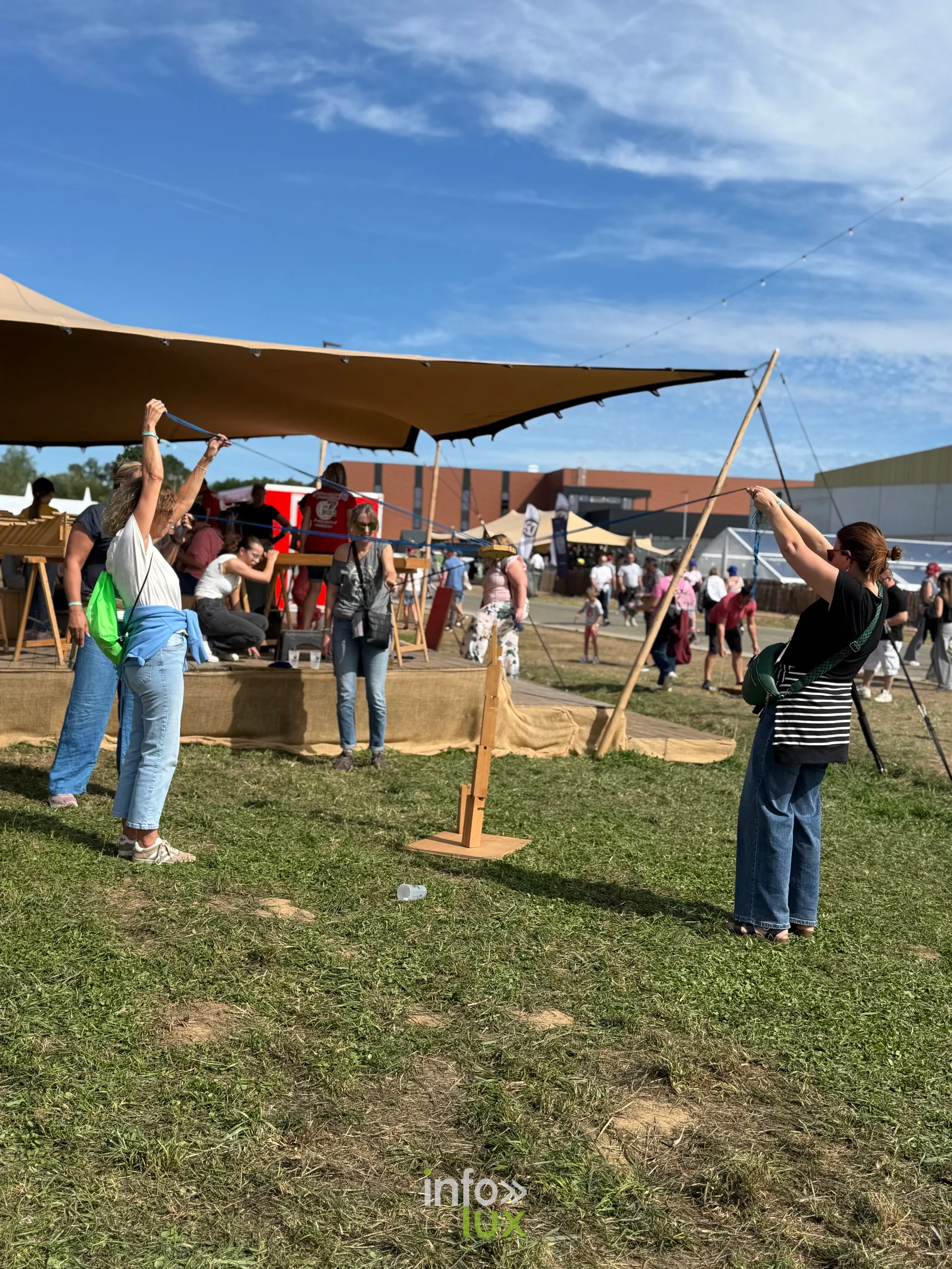 Des festivaliers sous une voile d'ombrage sur la plaine