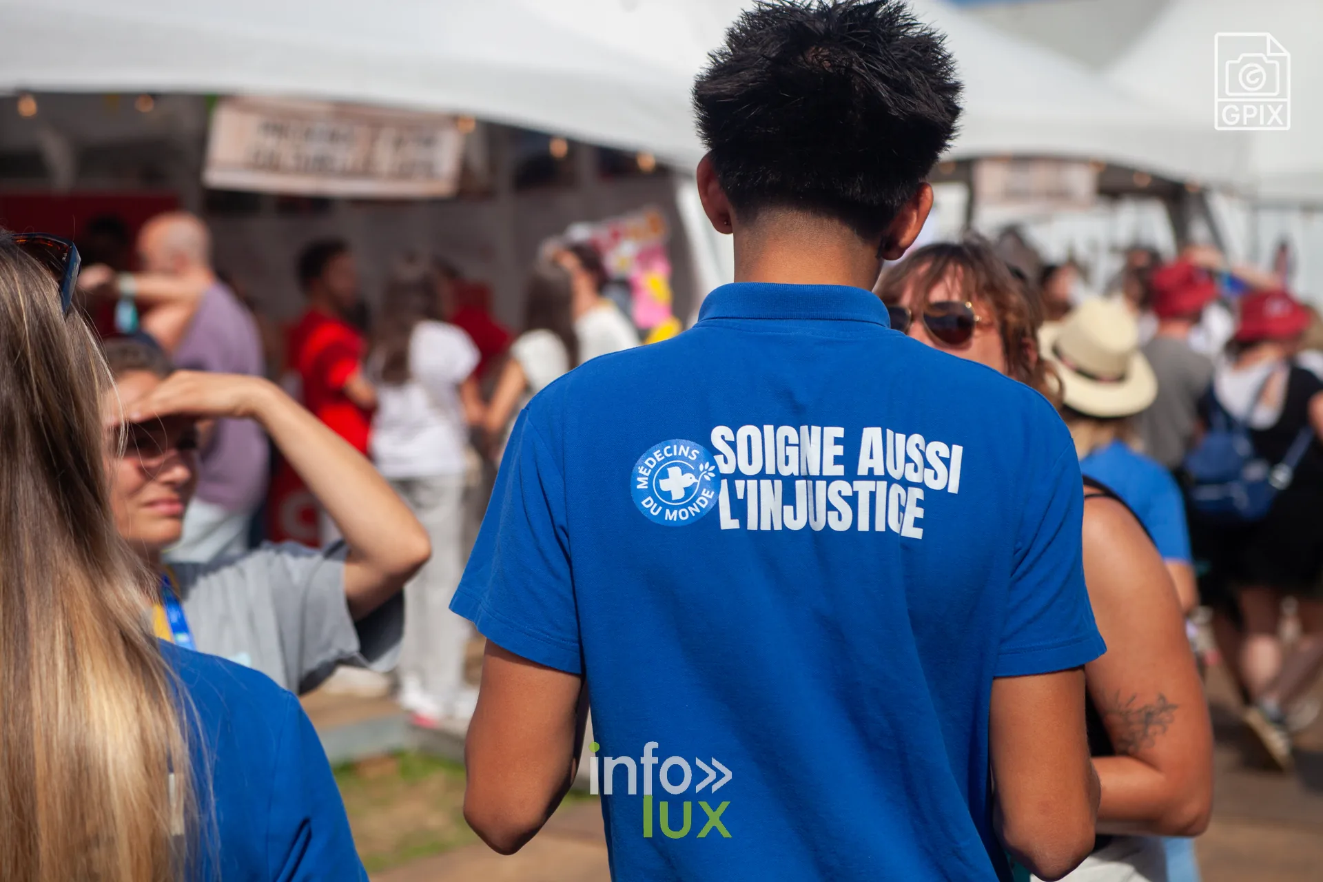 Un bénévole en polo « Soigne aussi l'injustice » au village associatif