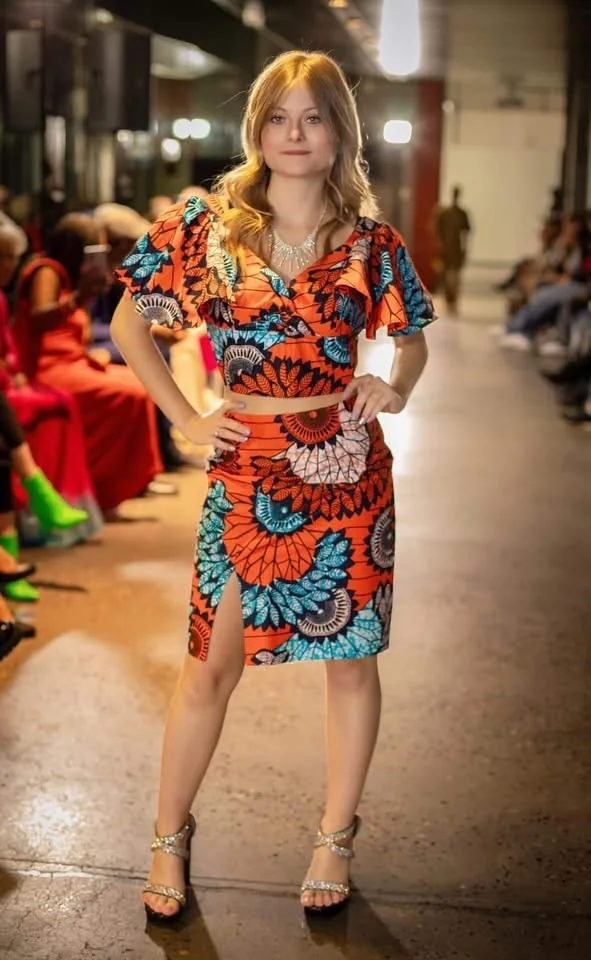Mannequin en ensemble en wax orange et bleu lors d'un défilé de la Liège Fashion Week