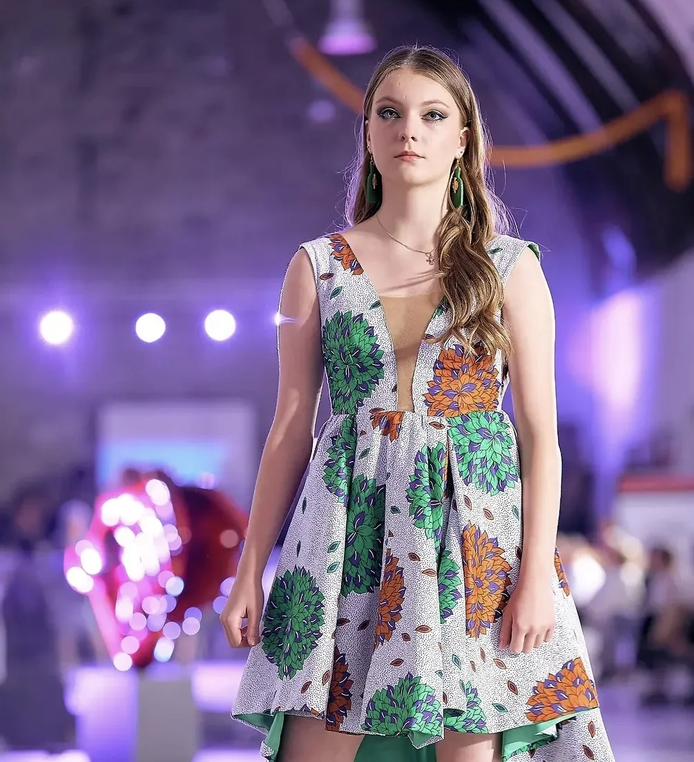 Jeune mannequin en robe à motifs verts sur le podium de la Liège Fashion Week
