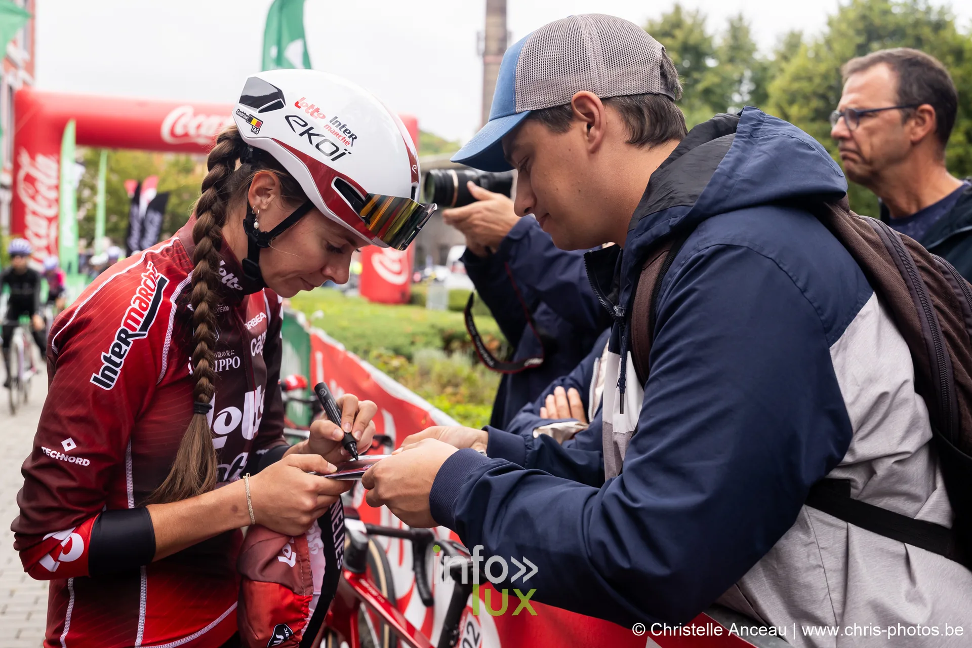 Une coureuse signe un autographe pour un spectateur au depart du Grand Prix de Wallonie a Seraing