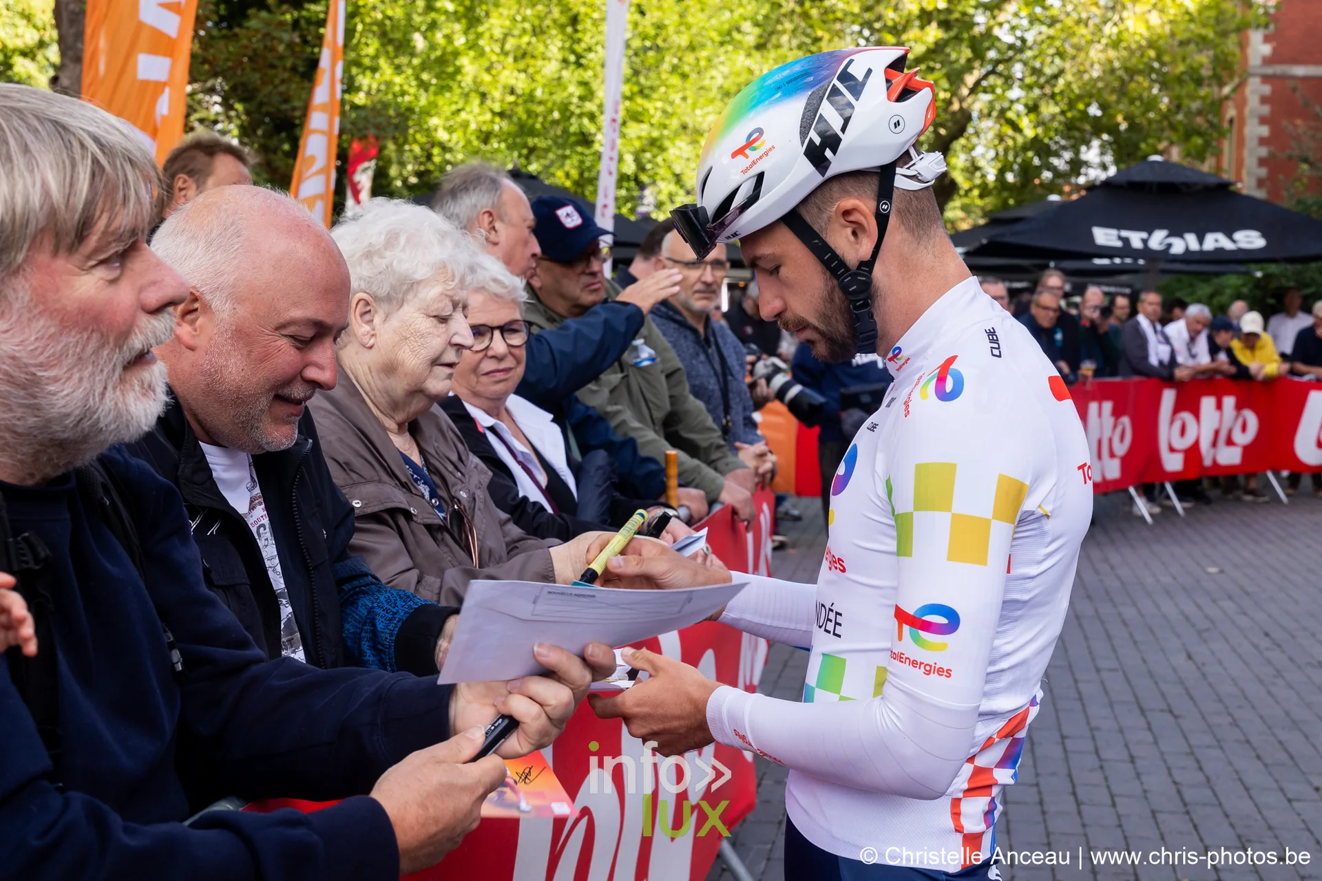 Coureur de TotalEnergies signant des autographes le long des barrieres Lotto a Seraing
