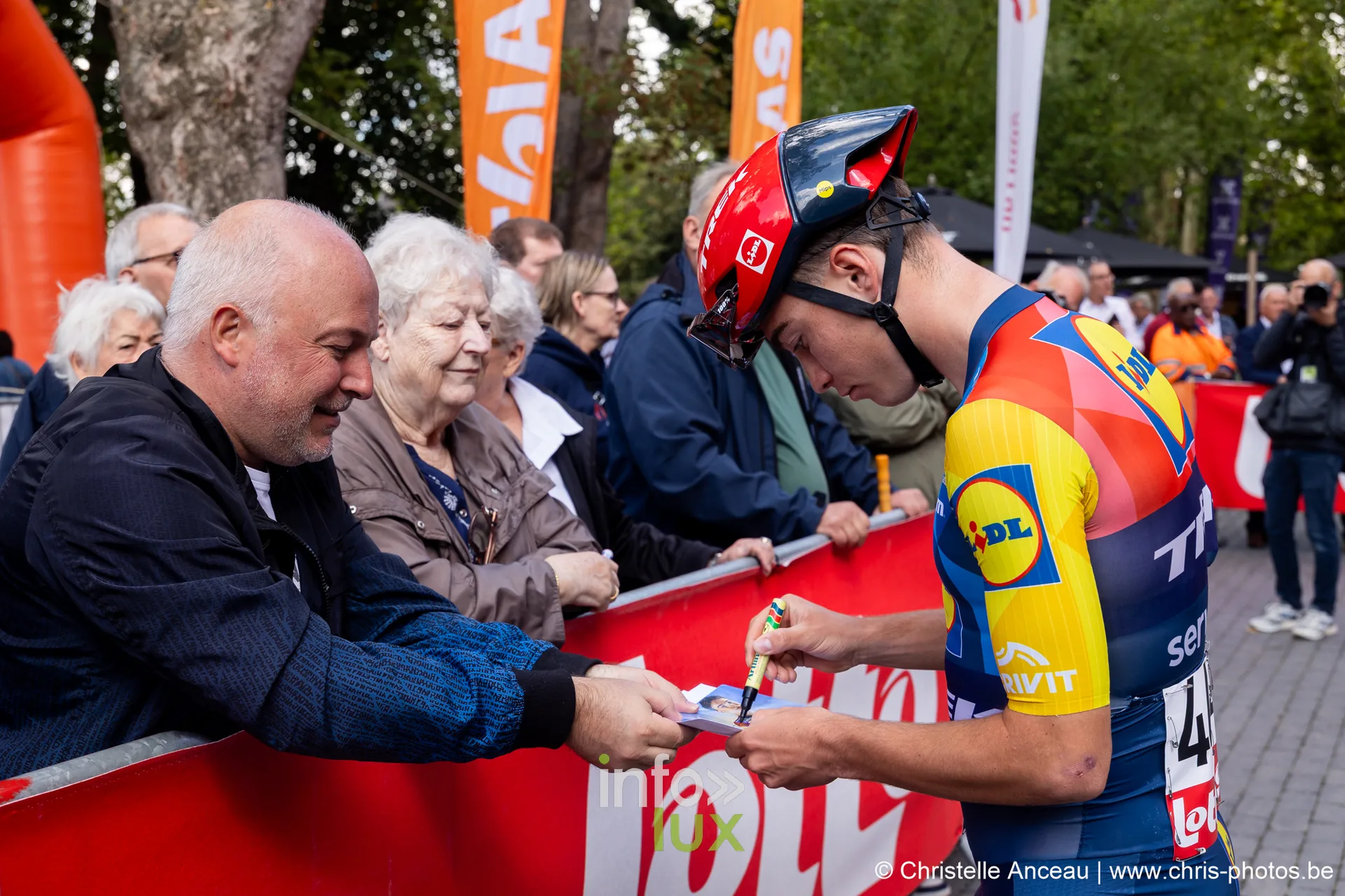 Coureur de Lidl-Trek en maillot jaune et bleu dedicace une carte au depart