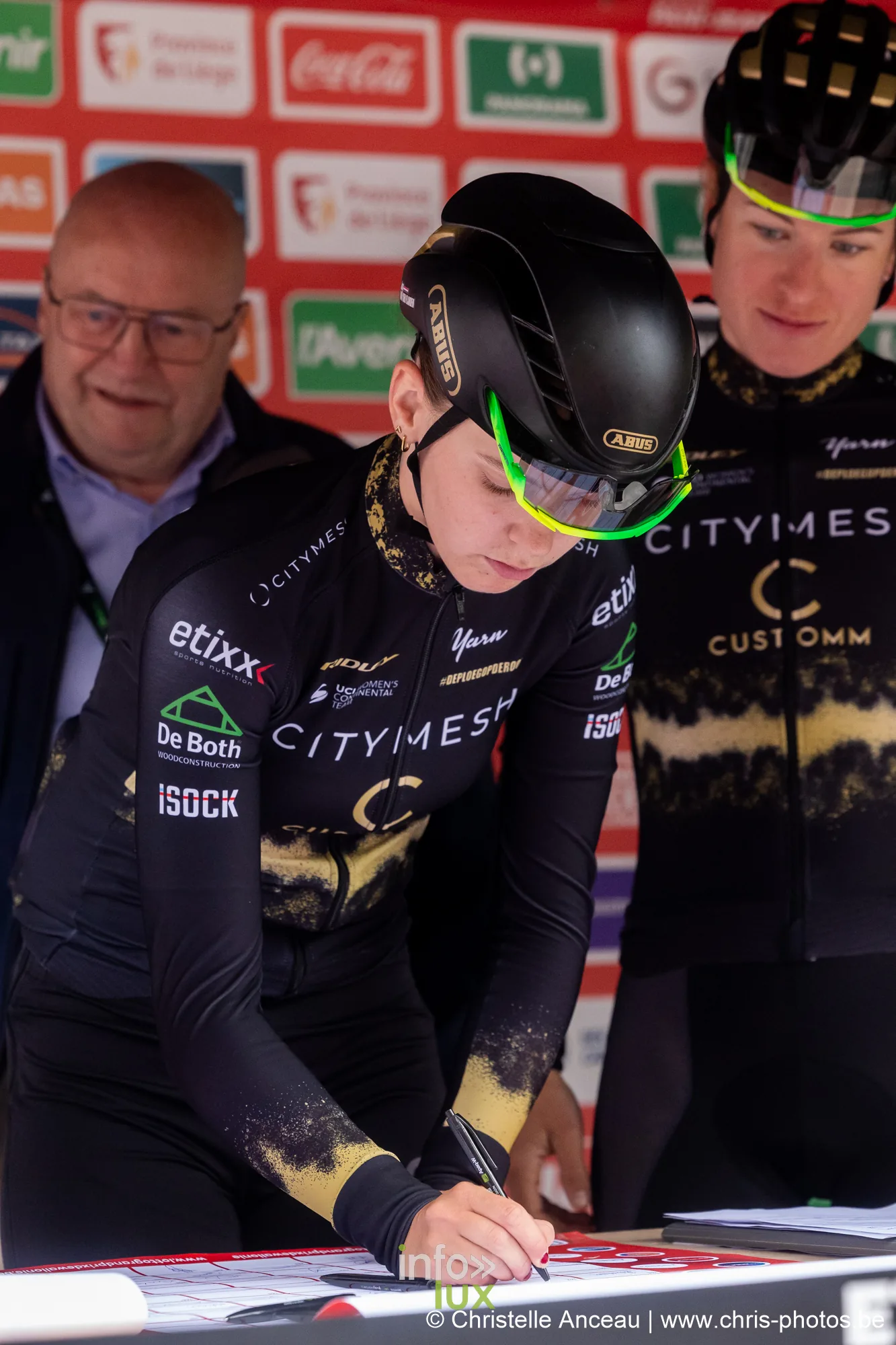Coureuse Citymesh en noir signant la feuille de depart devant le mur de sponsors