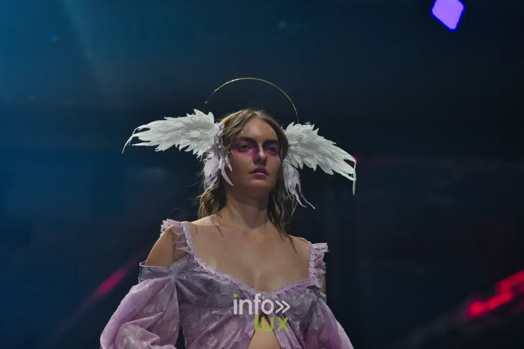 Coiffe d’ailes blanches et auréole dorée, chemise lilas aux épaules dénudées — Alimac, « Mystic Blossom », Lux Fashion Week 2026, Arlon