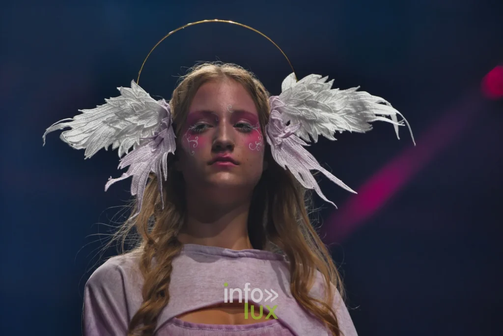 Portrait : coiffe d’ailes et auréole, tresses, haut lilas découpé — Alimac, « Mystic Blossom », Lux Fashion Week 2026, Arlon