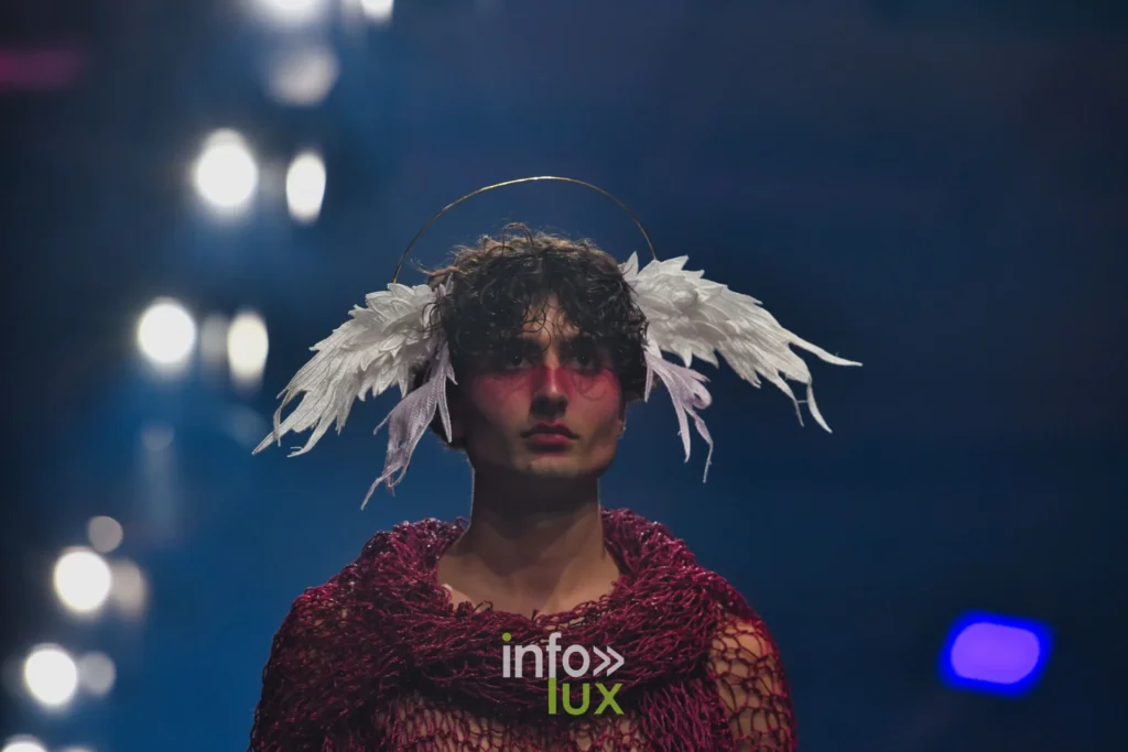 Maille ajourée bordeaux portée en châle, coiffe d’ailes blanches — Alimac, « Mystic Blossom », Lux Fashion Week 2026, Arlon