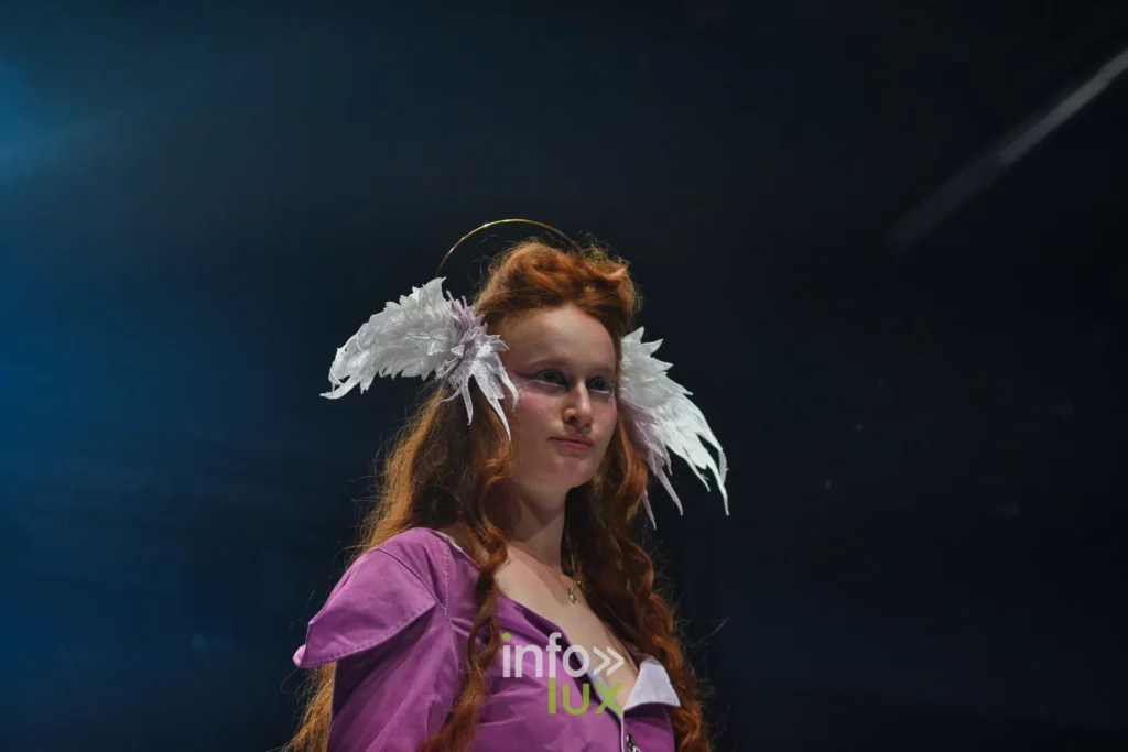 Robe violette à col blanc, cheveux roux, coiffe d’ailes — Alimac, « Mystic Blossom », Lux Fashion Week 2026, Arlon