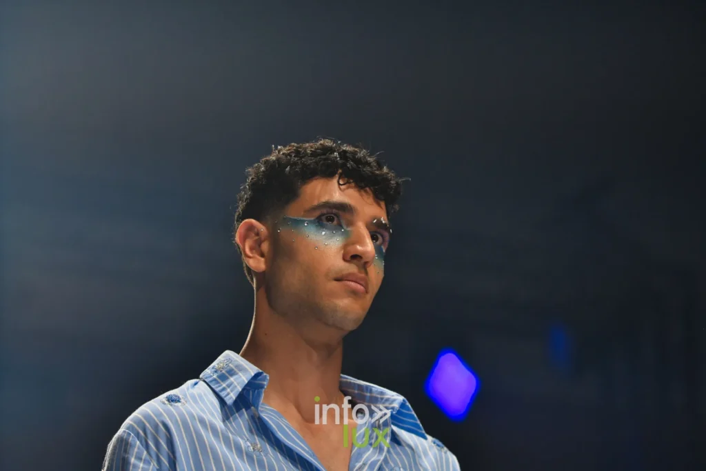 Portrait : chemise bleue à rayures, maquillage bleu autour des yeux — Violette Briel, « L’Héritage », Lux Fashion Week 2026, Arlon