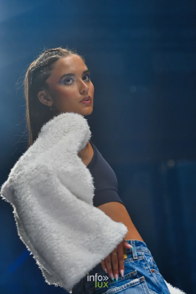 Veste blanche à longs poils tombée sur l’épaule, jean — Violette Briel, « L’Héritage », Lux Fashion Week 2026, Arlon