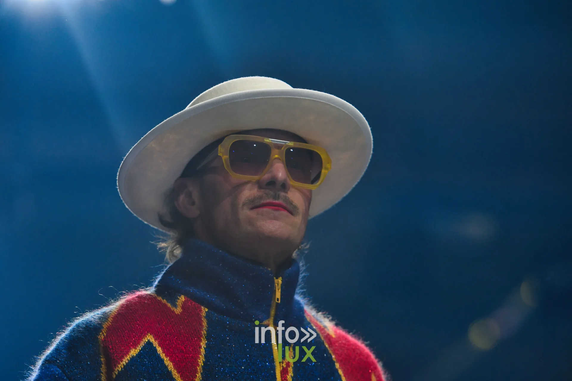 Veste zippée en maille bleu marine à éclairs rouge et jaune, chapeau blanc, lunettes jaunes — Damlaws, « The Dam Star », Lux Fashion Week 2026, Arlon