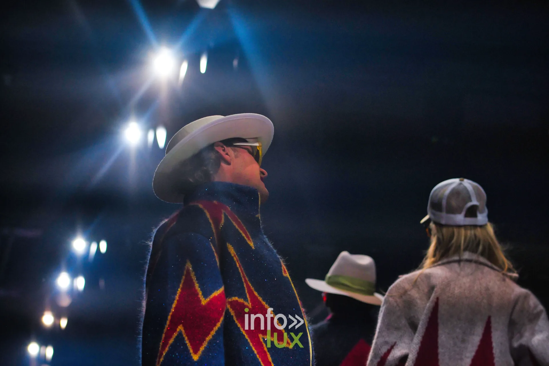 Veste bleu marine à éclairs rouge et jaune vue de profil, face aux autres silhouettes — Damlaws, « The Dam Star », Lux Fashion Week 2026, Arlon