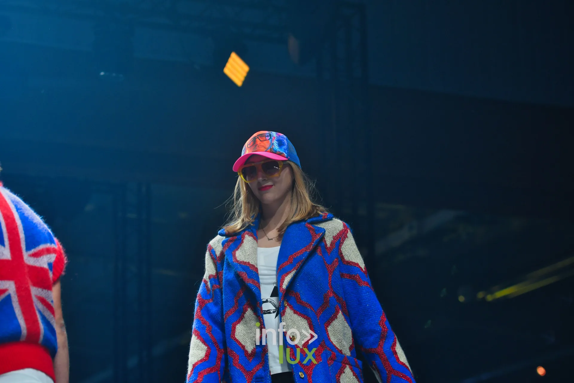 Manteau en maille bleu roi et écru à motifs rouges, casquette multicolore — Damlaws, « The Dam Star », Lux Fashion Week 2026, Arlon