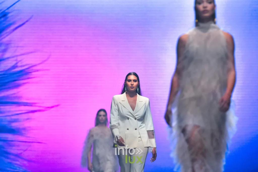 Tailleur-pantalon crème à manches transparentes, entre deux robes en tulle à volants — Francini_K, « La géométrie des fleurs », Lux Fashion Week 2026, Arlon