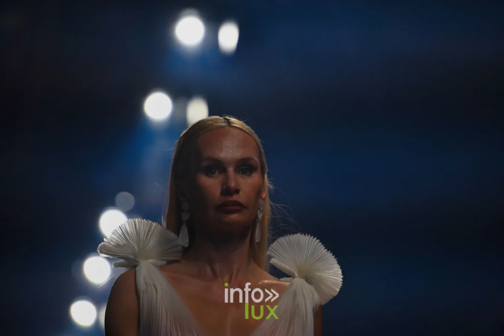Robe blanche à encolure en V et épaulettes plissées en éventail — Francini_K, « La géométrie des fleurs », Lux Fashion Week 2026, Arlon