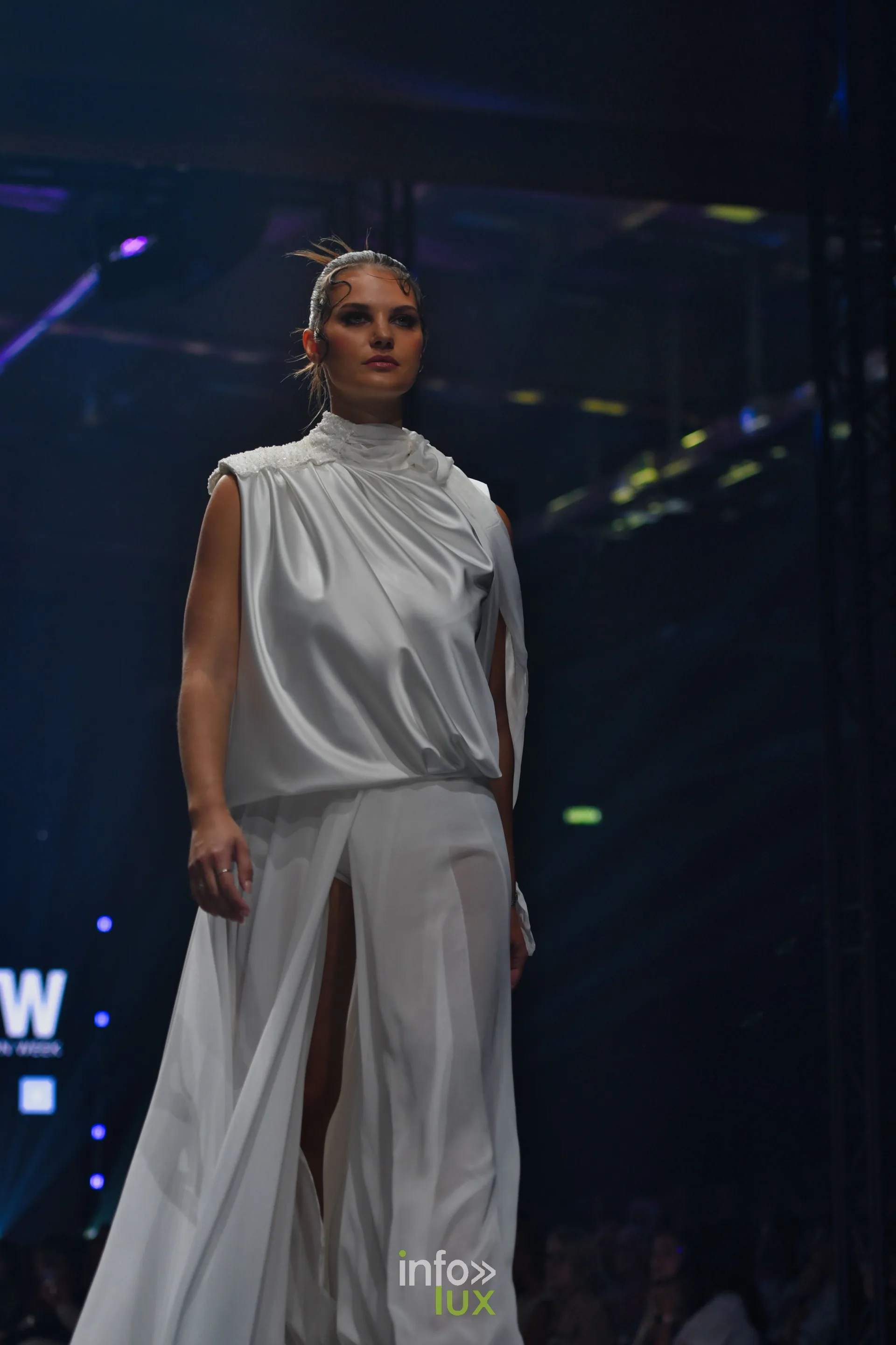 Haut en satin blanc à col montant et pantalon large blanc fendu, pan de voile, collection « Meraki bloom » d’Hélène Guiot, Lux Fashion Week 2026, Arlon