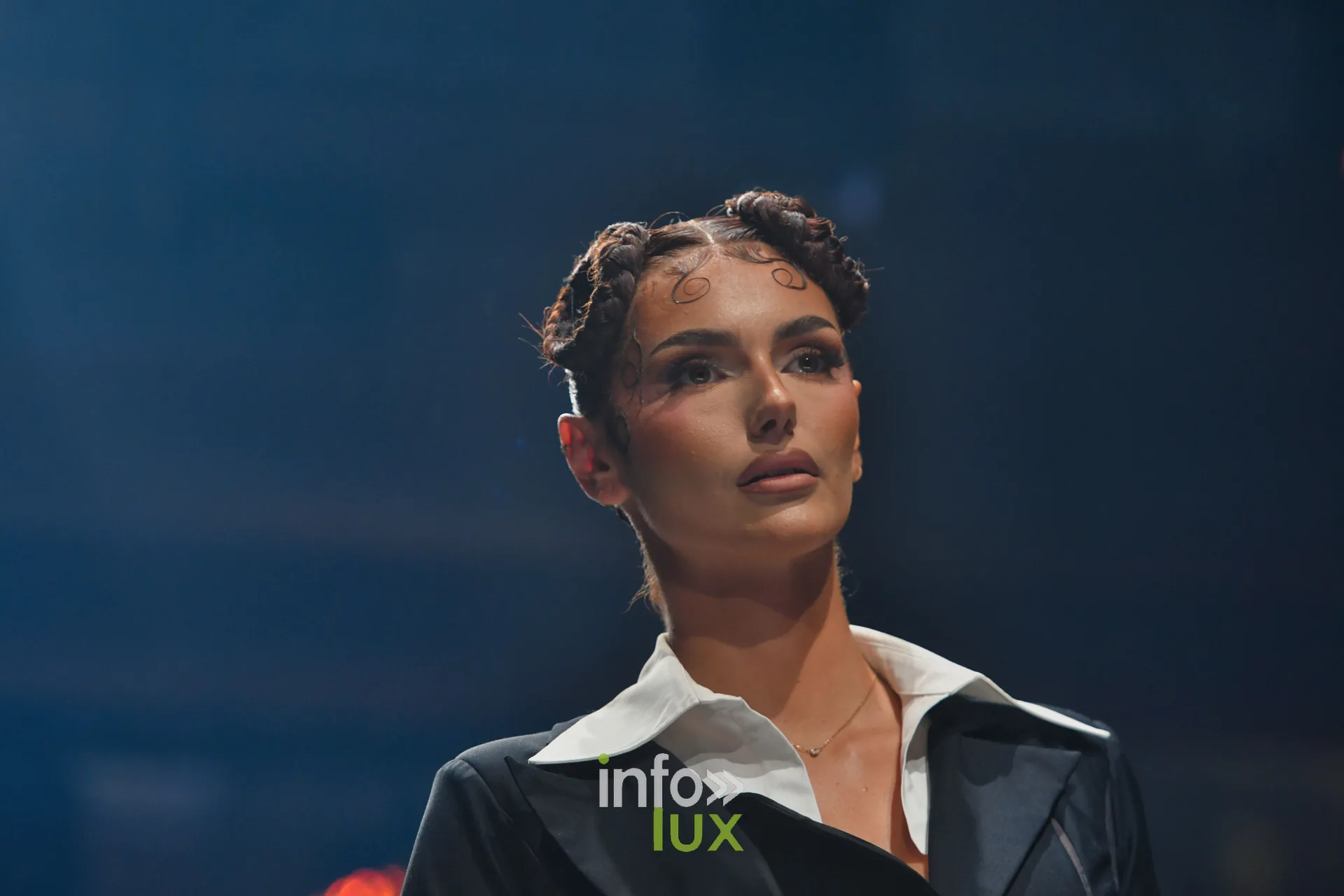 Veste noire à grand col blanc, cheveux tressés plaqués — R. Lopes, « Raízes d’Ouro », Lux Fashion Week 2026, Arlon