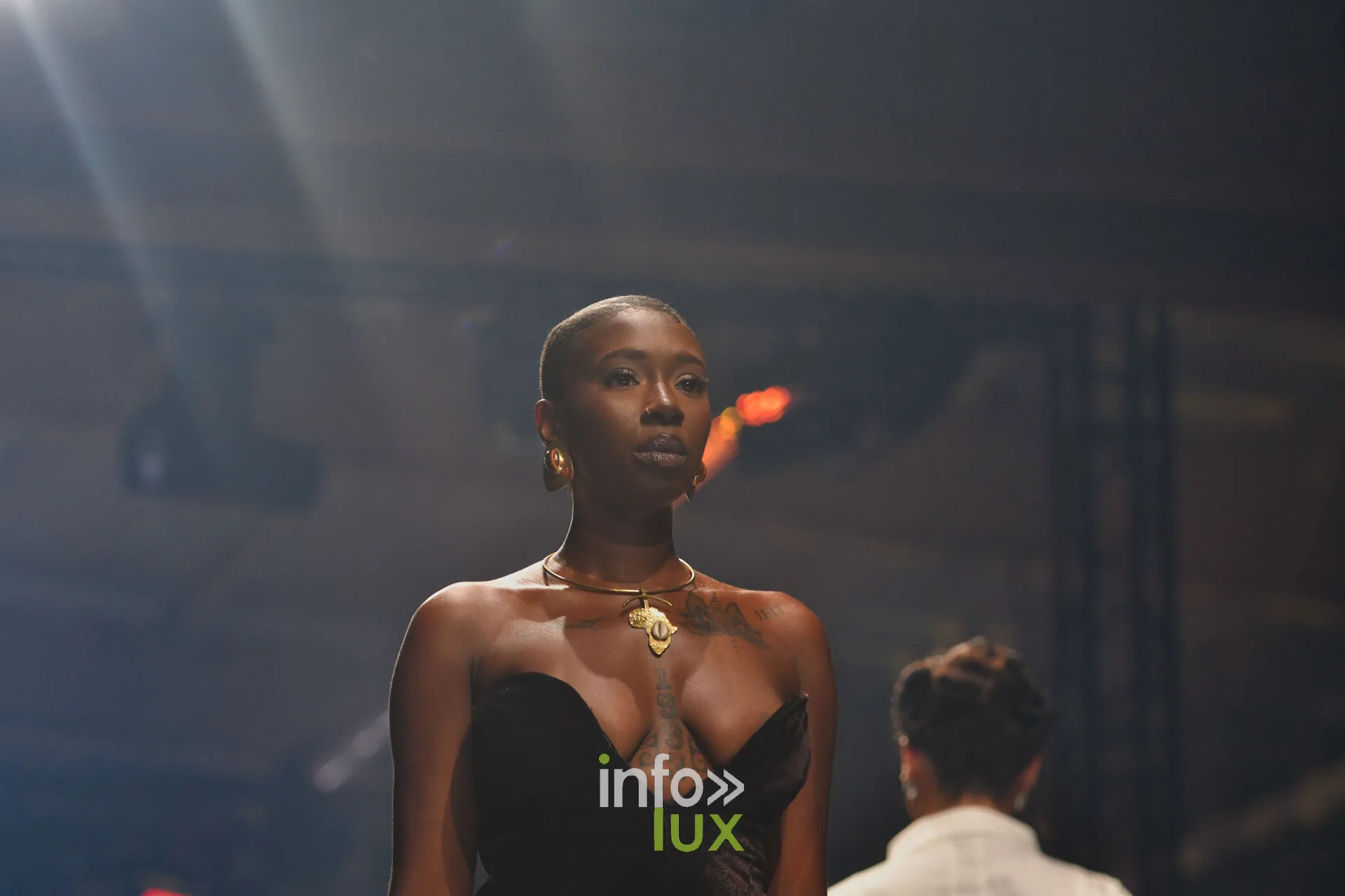 Robe bustier noire et collier doré à pendentif — R. Lopes, « Raízes d’Ouro », Lux Fashion Week 2026, Arlon