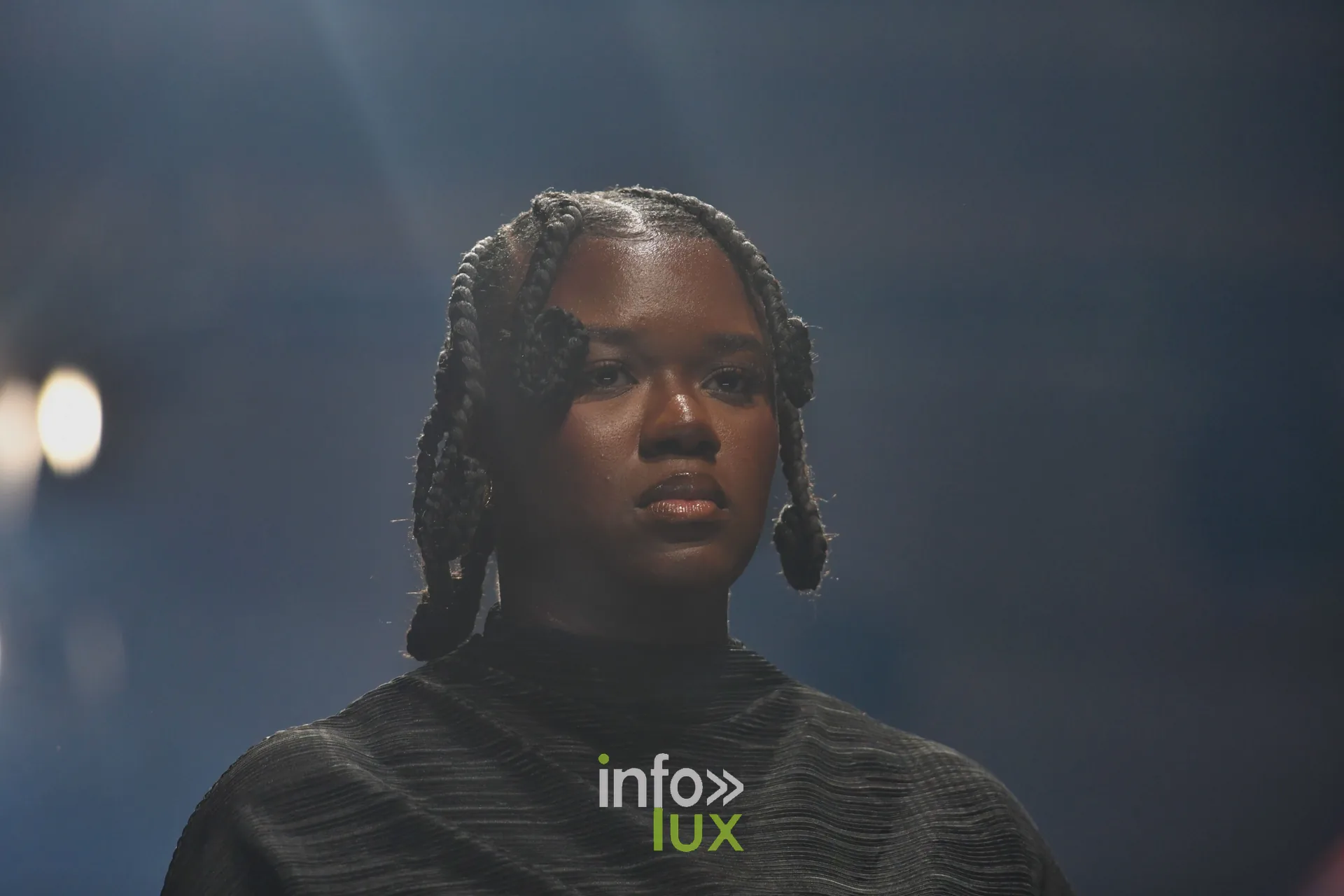 Haut noir texturé à col montant, tresses nouées — R. Lopes, « Raízes d’Ouro », Lux Fashion Week 2026, Arlon