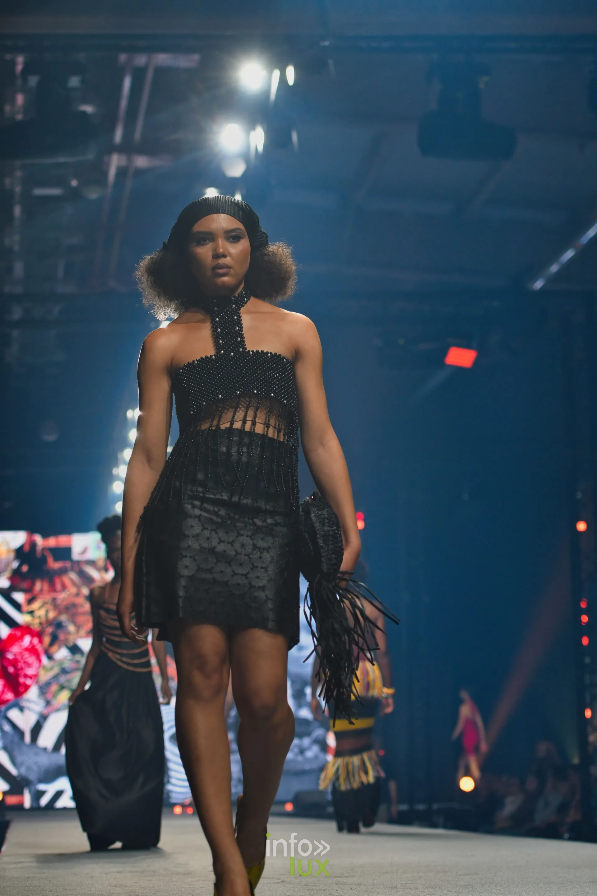 Bustier noir perlé à franges et col montant, jupe courte noire texturée — R. Lopes, « Raízes d’Ouro », Lux Fashion Week 2026, Arlon