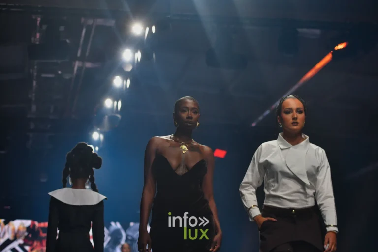 Trois silhouettes sur le podium : robe noire à grand col blanc, robe bustier noire, chemise blanche et pantalon noir — R. Lopes, « Raízes d’Ouro », Lux Fashion Week 2026, Arlon