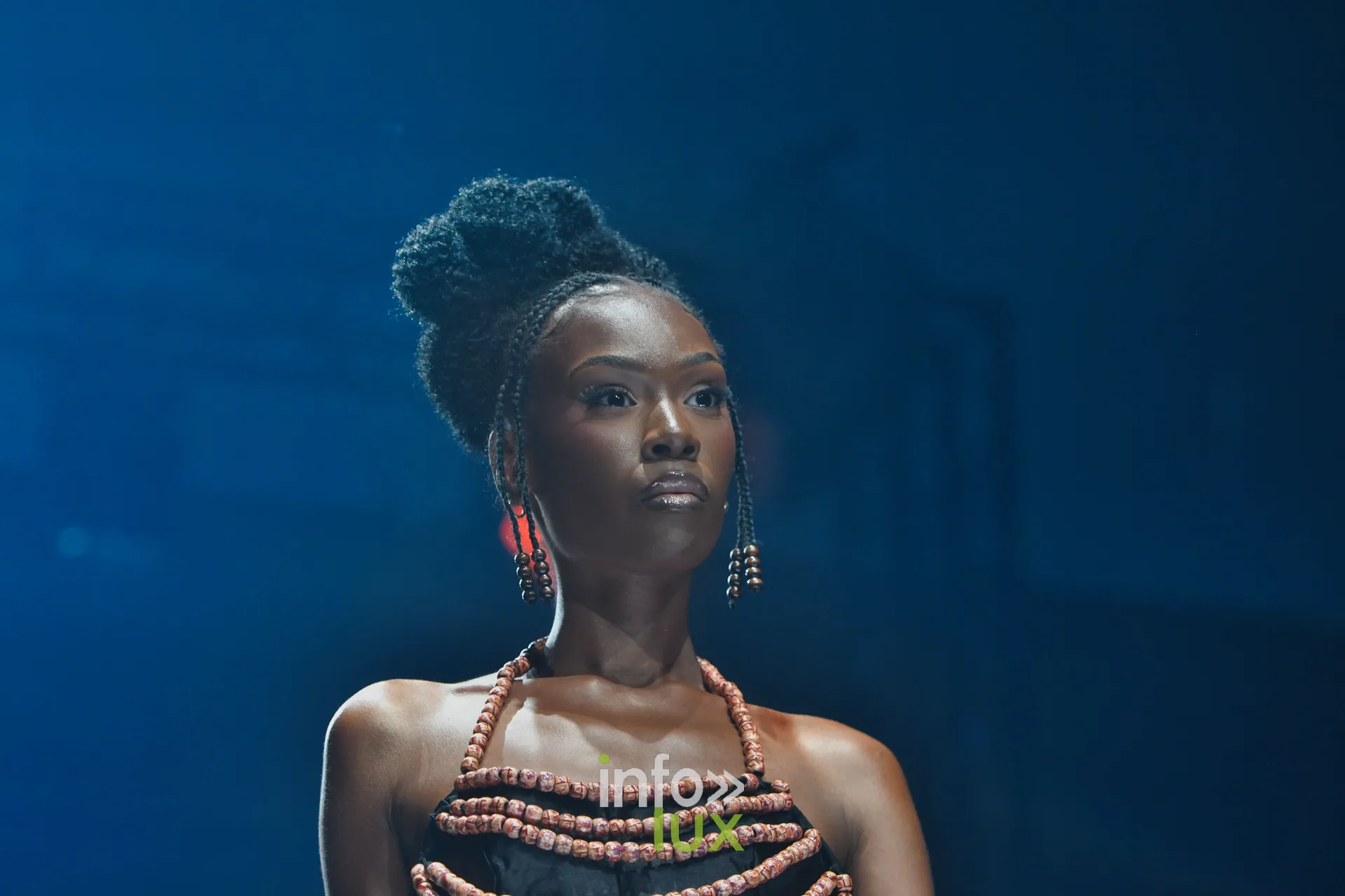 Haut à rangs de perles orangées, chignon et boucles d’oreilles pendantes — R. Lopes, « Raízes d’Ouro », Lux Fashion Week 2026, Arlon