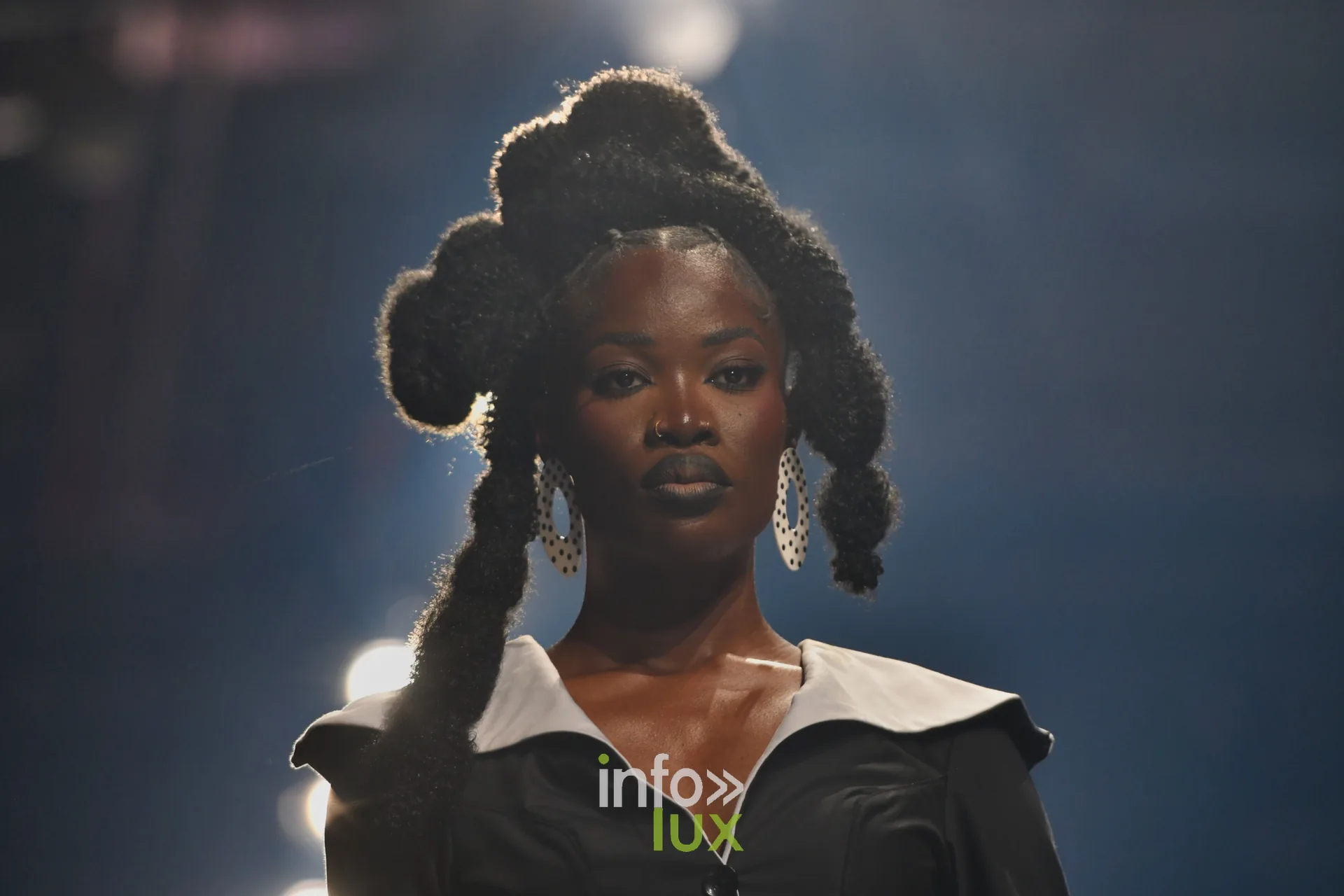 Robe noire à grand col blanc, coiffure en chignons sculptés — R. Lopes, « Raízes d’Ouro », Lux Fashion Week 2026, Arlon