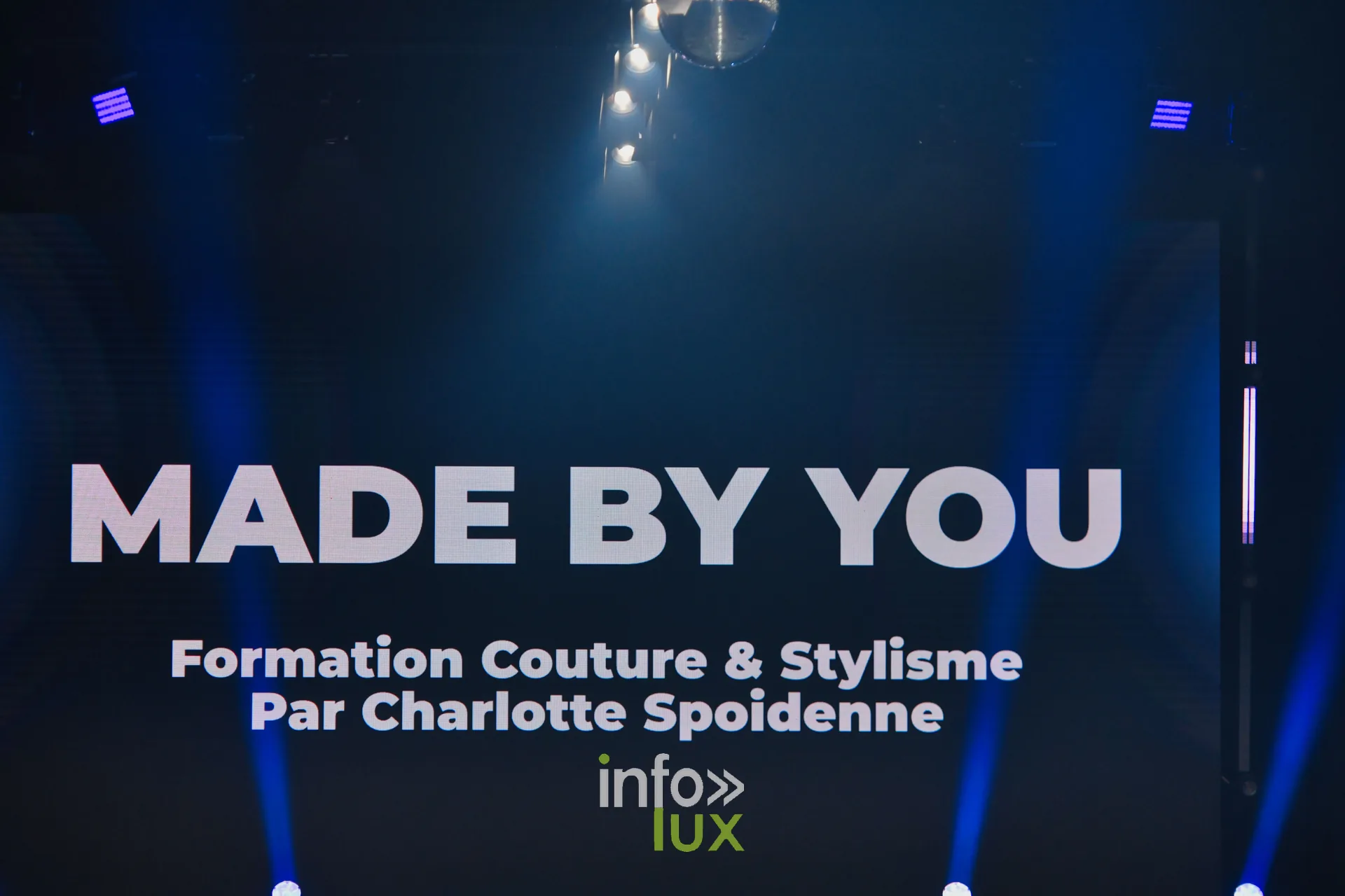 L’écran de scène affiche « Made by You — Formation Couture & Stylisme par Charlotte Spoidenne » avant le passage — Made by You, école de couture et de stylisme de Charlotte Spoidenne, Lux Fashion Week 2026, Arlon